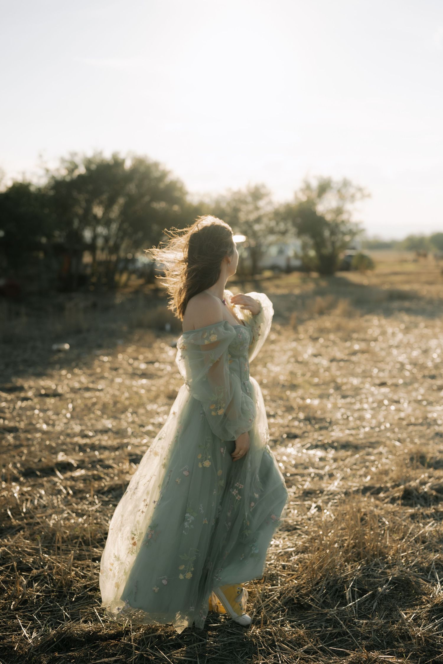 A dreamy sequence of a person in a flowing white dress dancing and twirling in a sunlit field at golden hour.