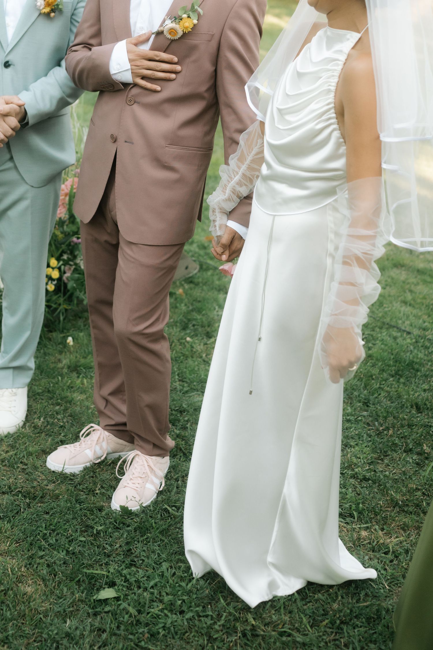 Wedding party poses playfully on grass showing off their mint green and brown attire with white gown.
