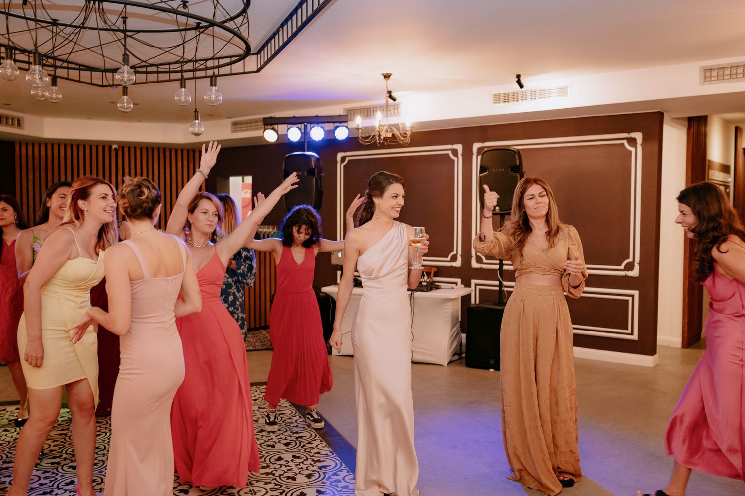 A group of people dancing together in an indoor venue with wooden walls and track lighting.