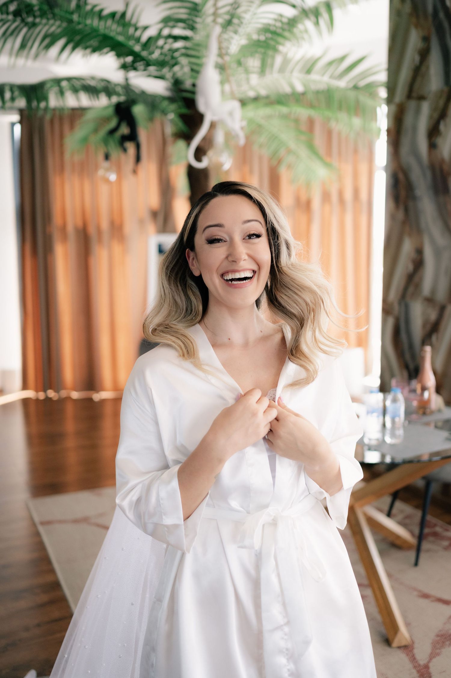 A series of four candid photos showing joyful laughter and natural expressions in a white outfit against a tropical backdrop.