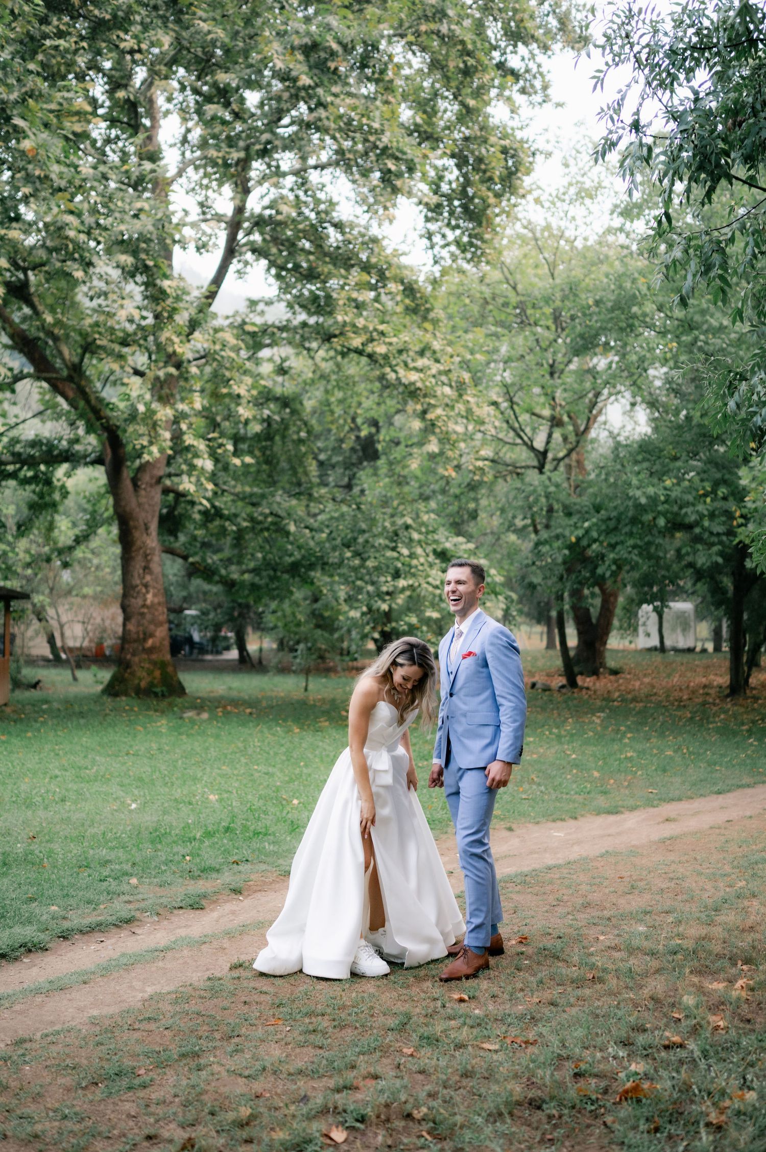 A couple shares a romantic moment together in a lush green park setting on their wedding day.