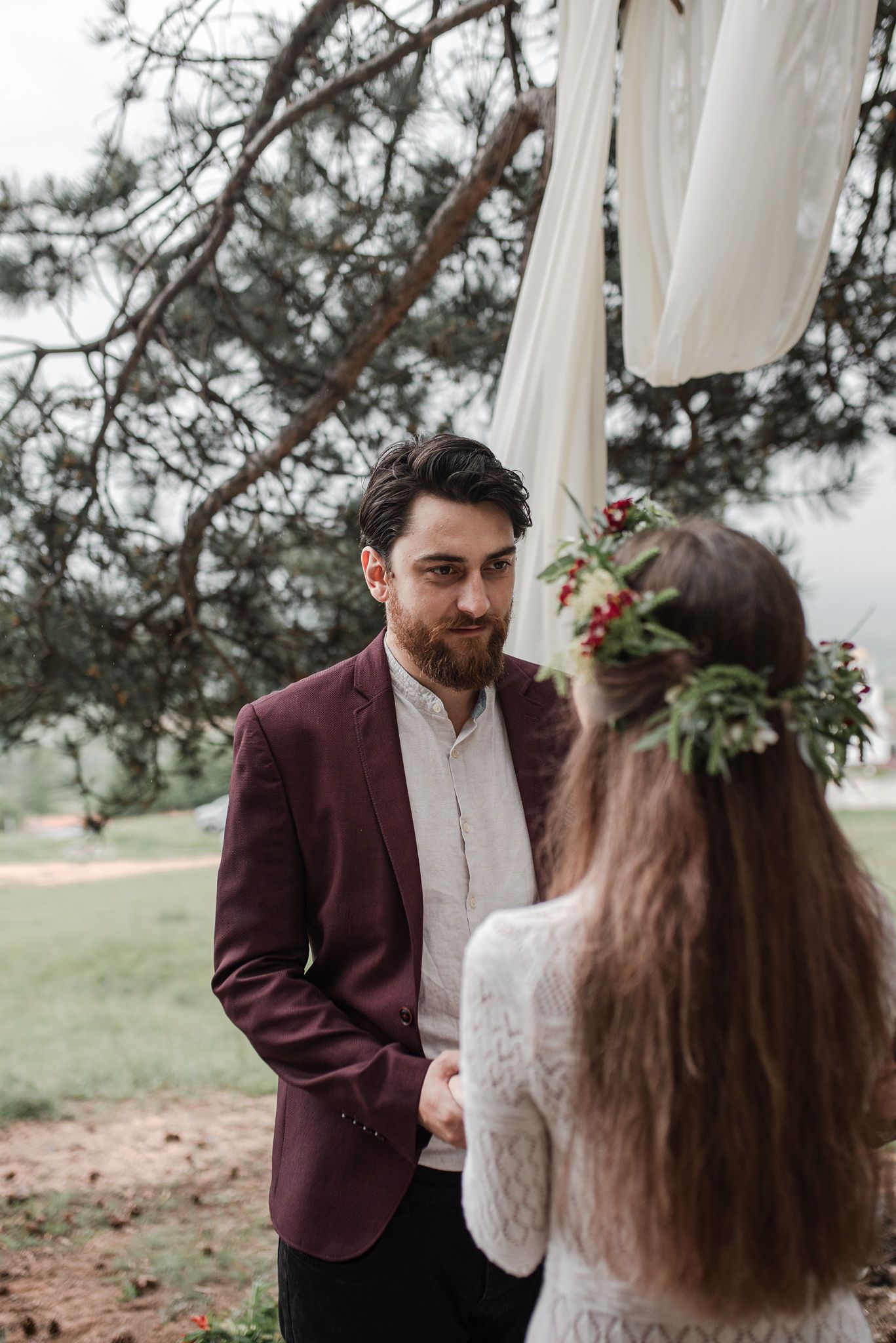 A couple shares intimate moments during their outdoor wedding ceremony under pine trees.