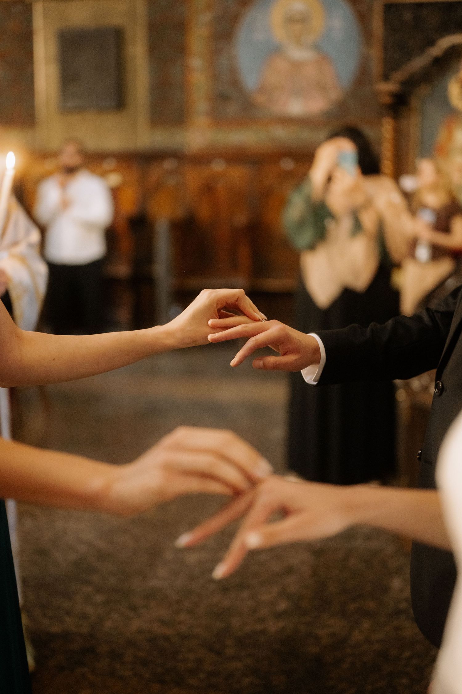 Close-up of hands reaching for each other during a dance at an elegant event with religious iconography in the background.