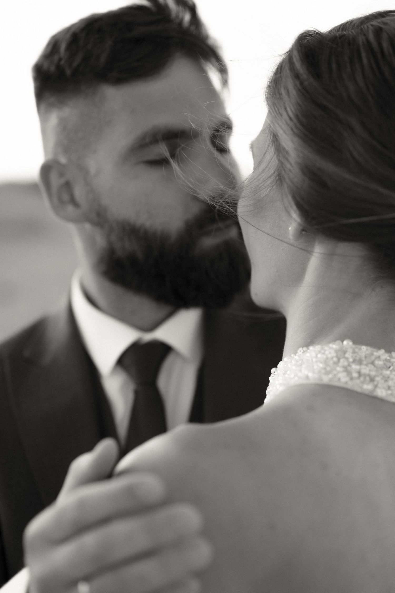 Black and white close-up of a bearded groom about to kiss his bride on their wedding day.