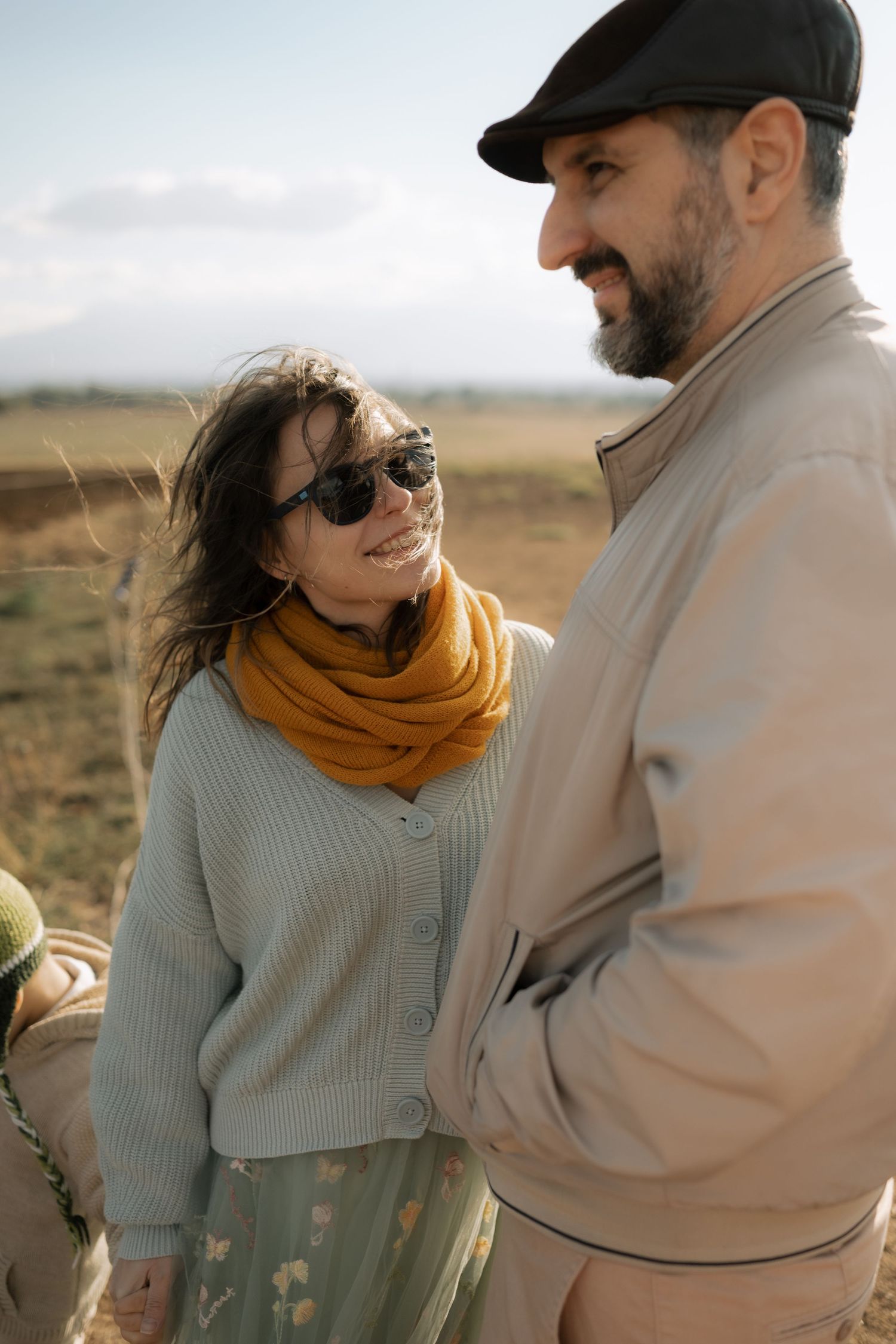 A couple in casual autumn attire sharing an intimate moment outdoors in a desert landscape.