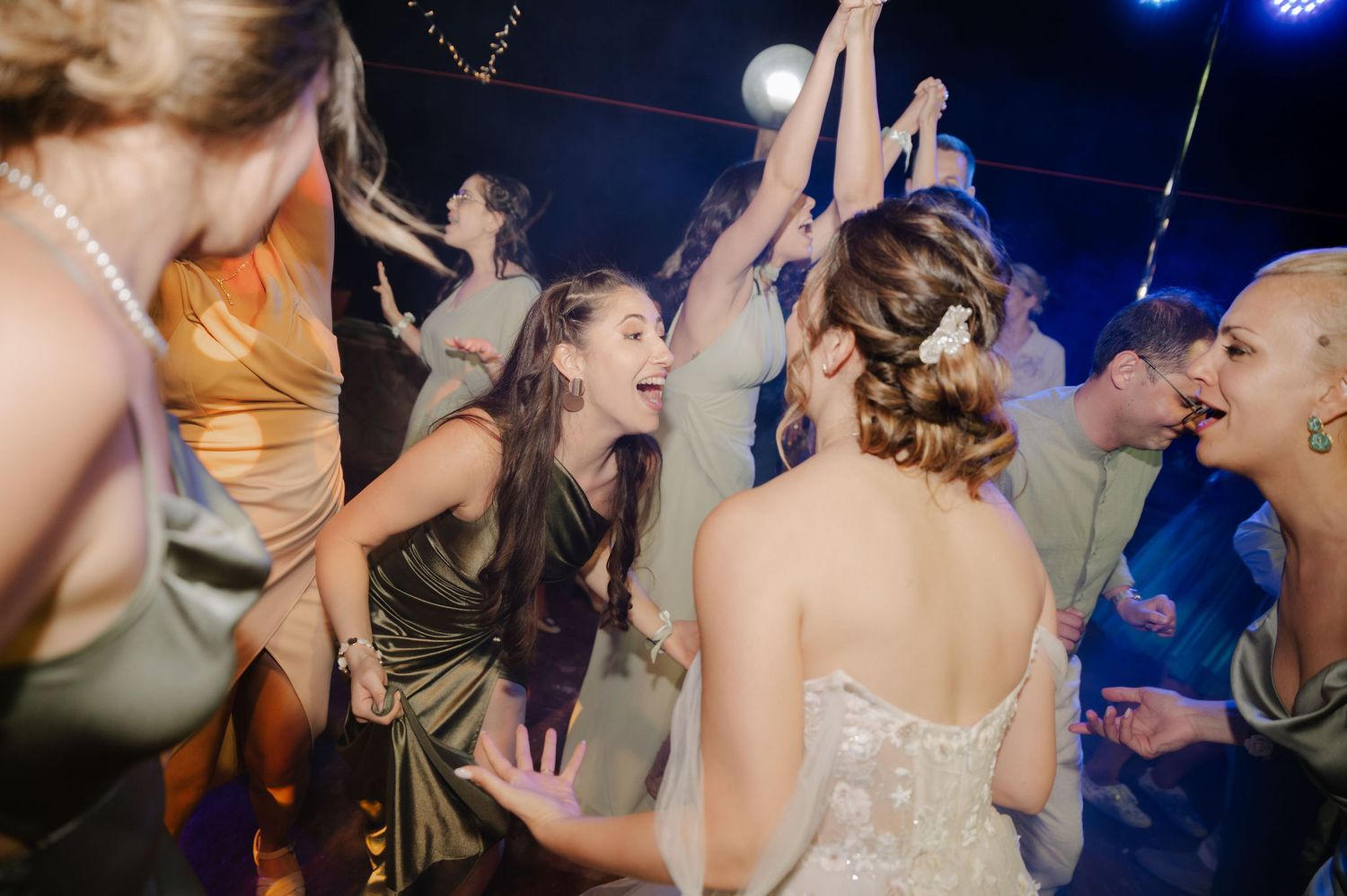 People dancing and celebrating at a lively nightclub party with colorful lighting and energetic atmosphere.