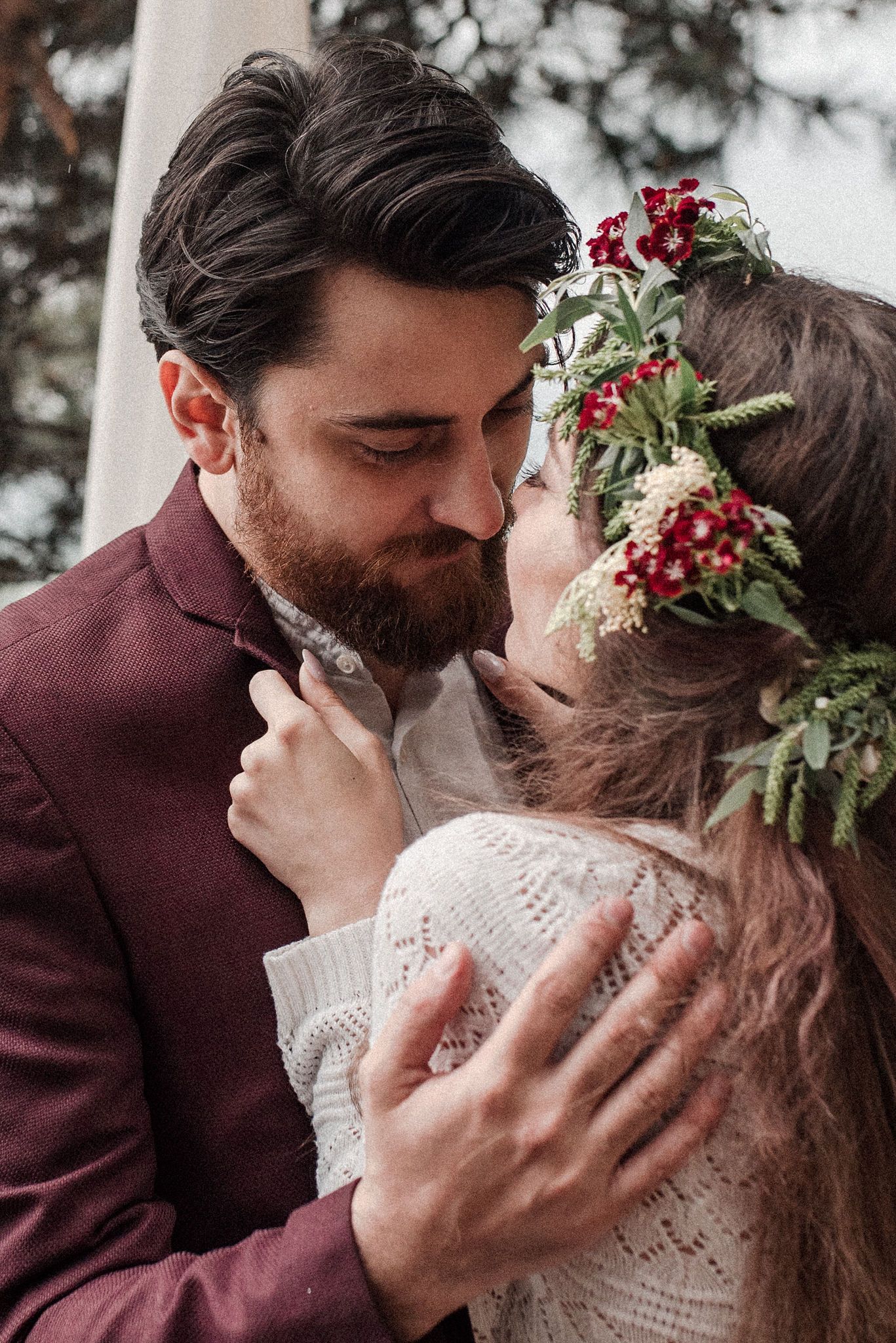 A romantic wedding moment captured in a series of intimate kisses between a couple, with burgundy florals and white lace details.