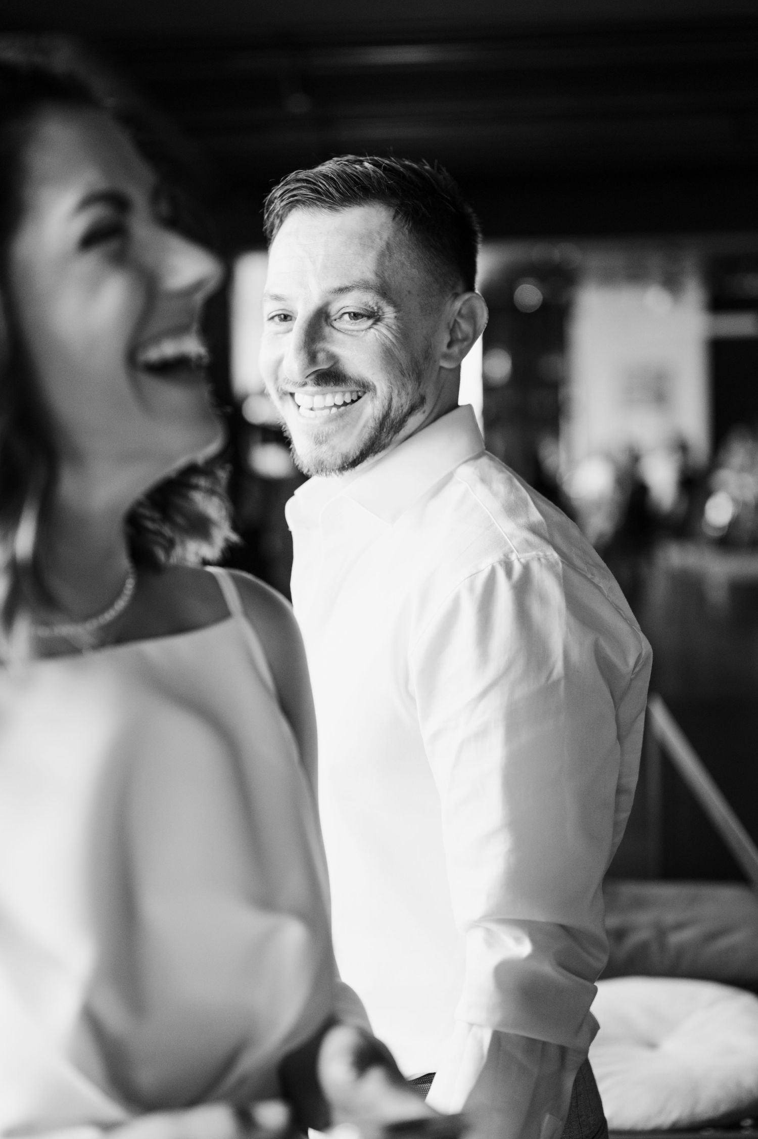 Black and white photo sequence showing a person in a white dress shirt turning and smiling in a candid moment.