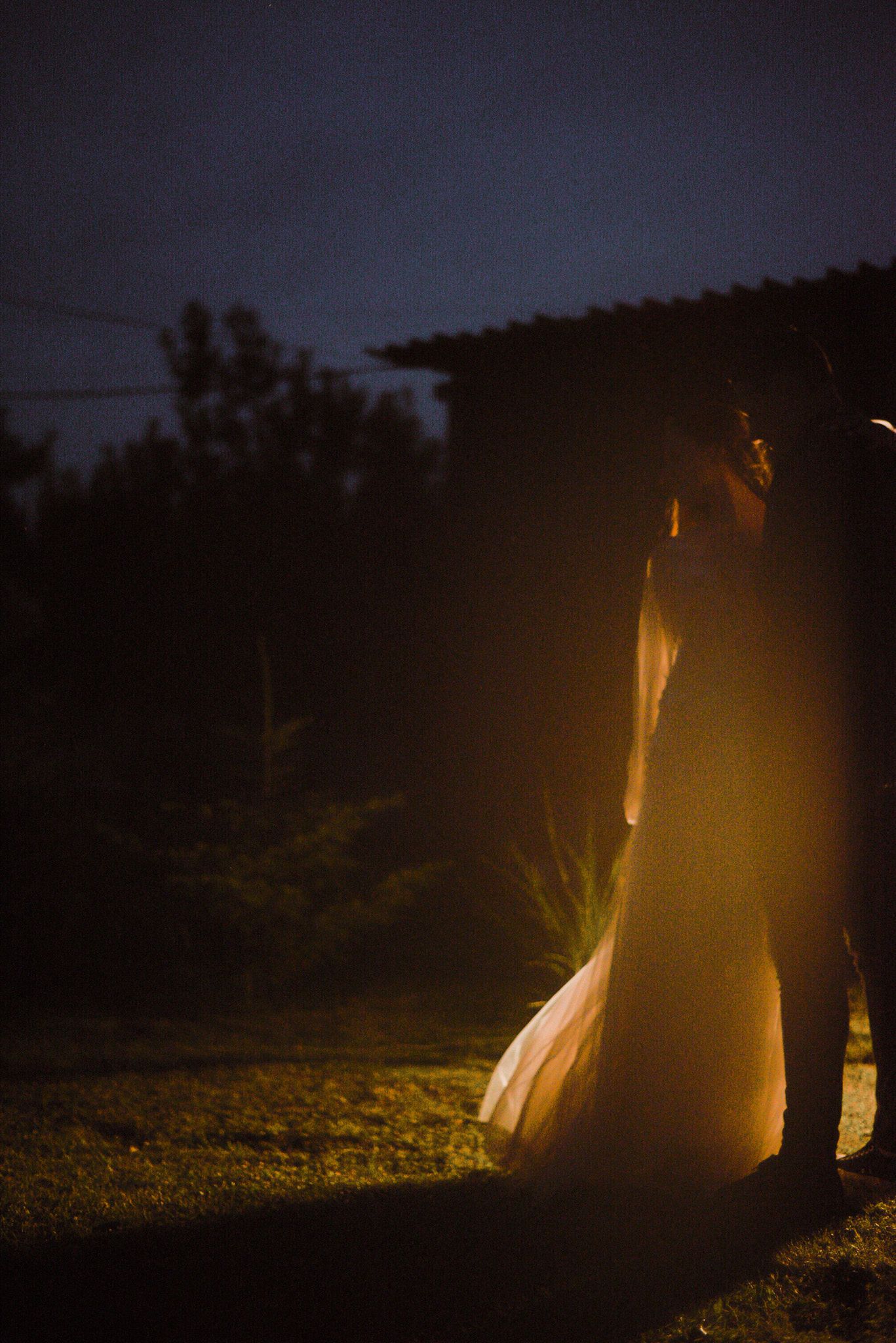 A series of dark silhouettes illuminated by warm glowing lights against a nighttime background.