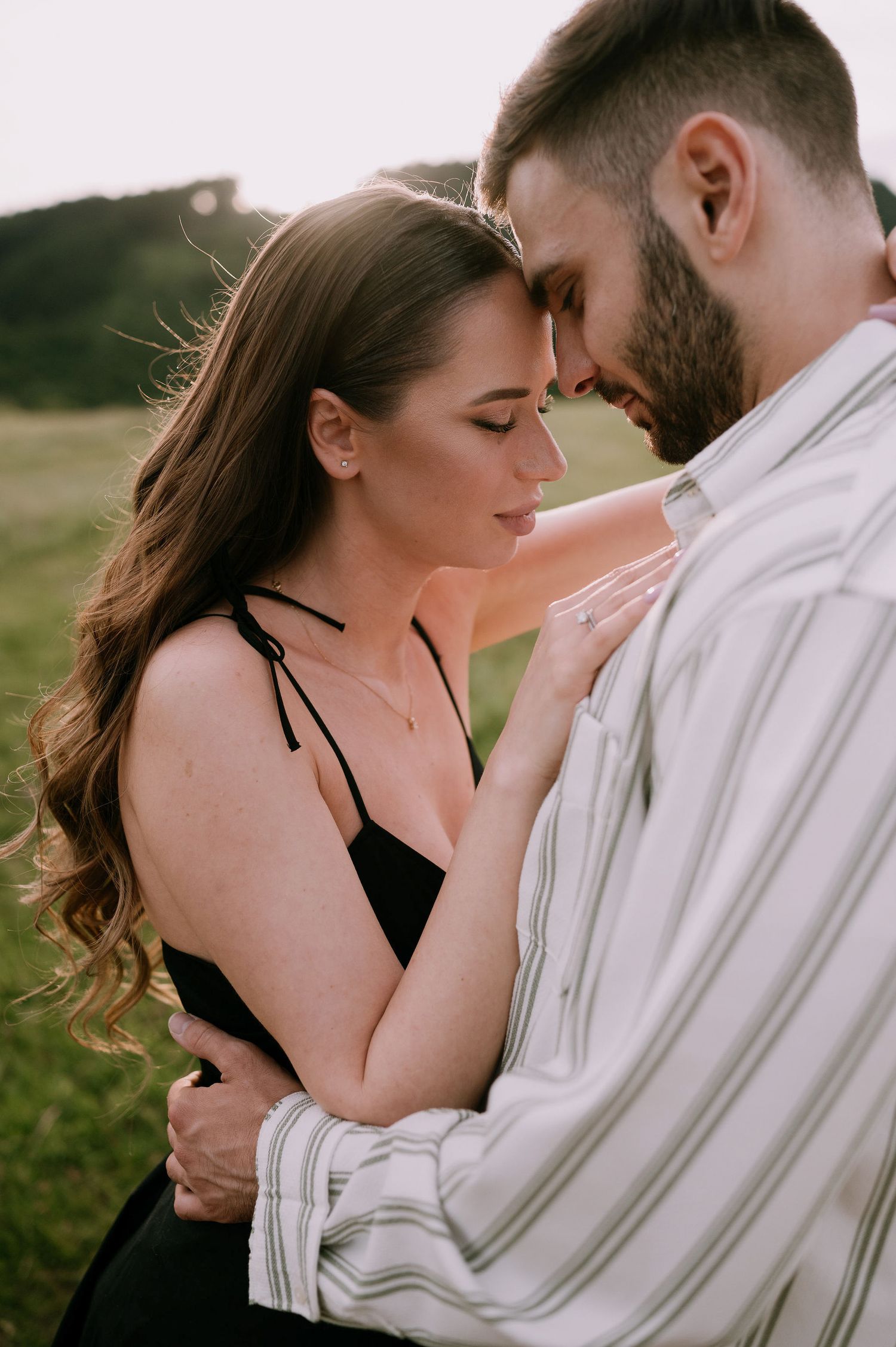 A romantic couple embraces in an intimate outdoor photoshoot series wearing black and white outfits.