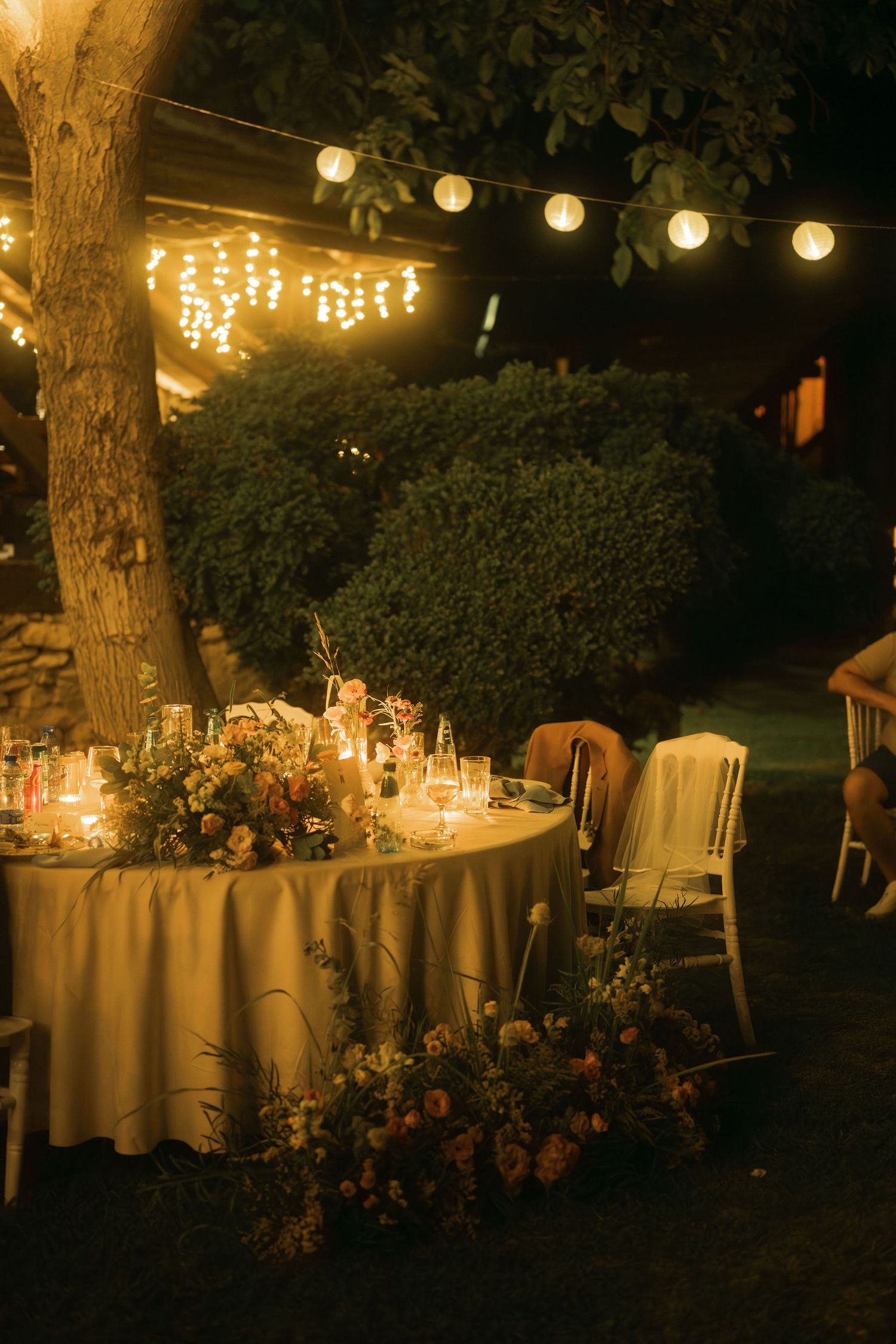 Romantic outdoor evening wedding reception setup with round tables and string lights creating an enchanting atmosphere.