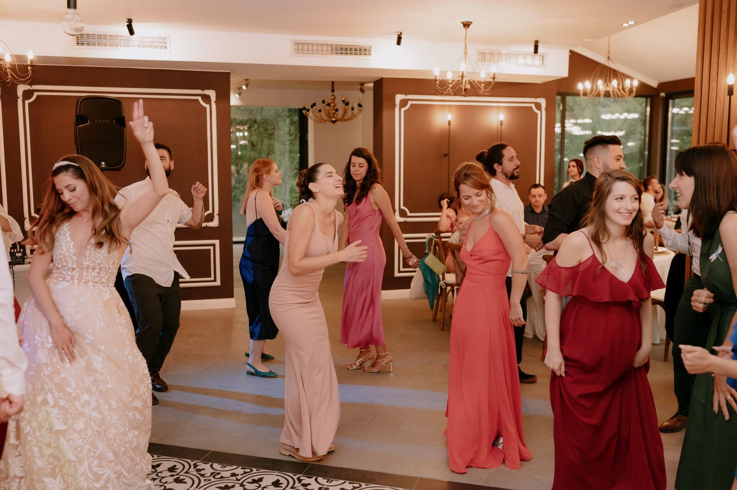 Wedding party guests dancing and celebrating on the dance floor at an elegant indoor reception venue.