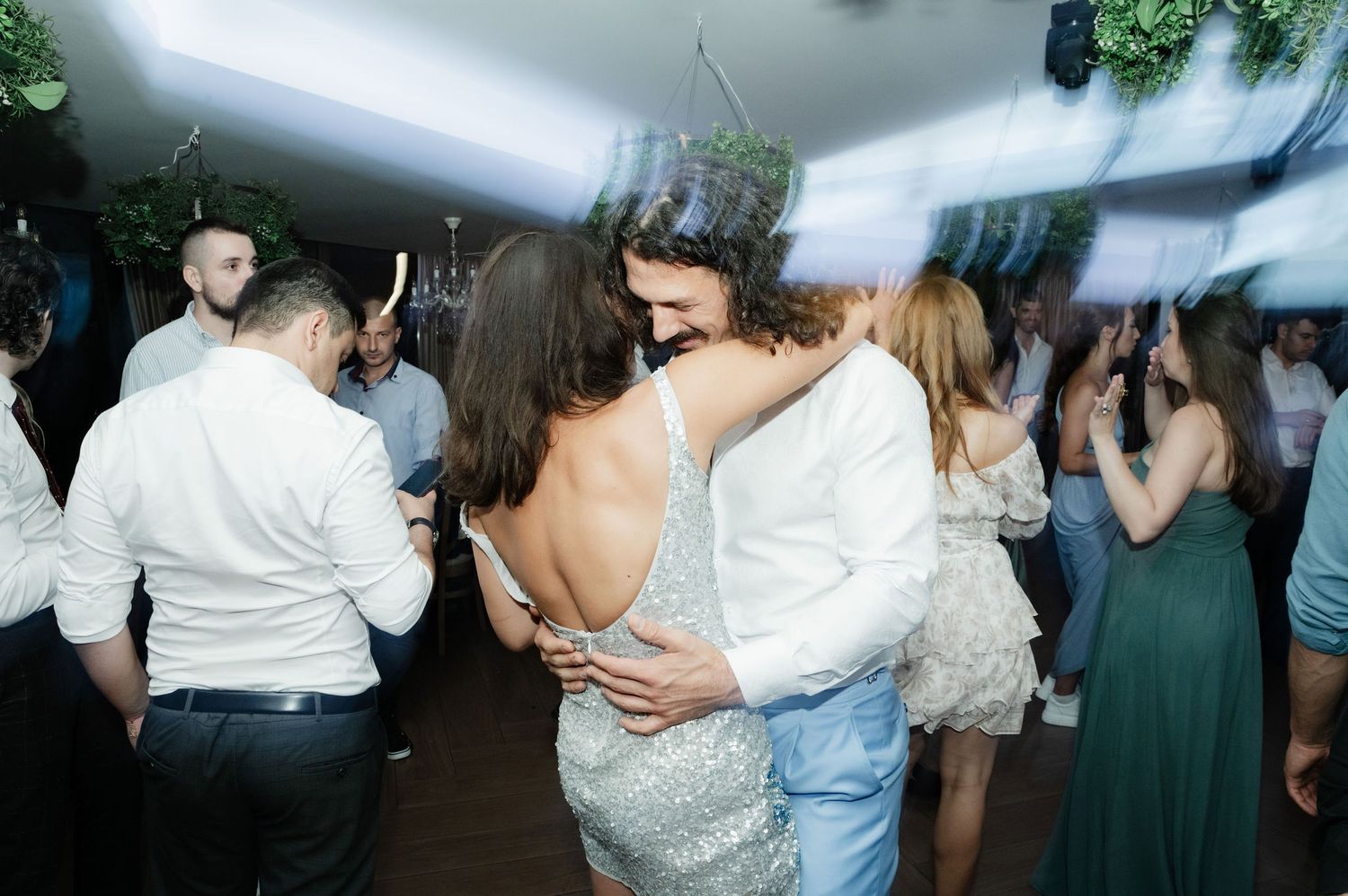 Couples dancing together on a dimly lit dance floor during a wedding reception celebration.