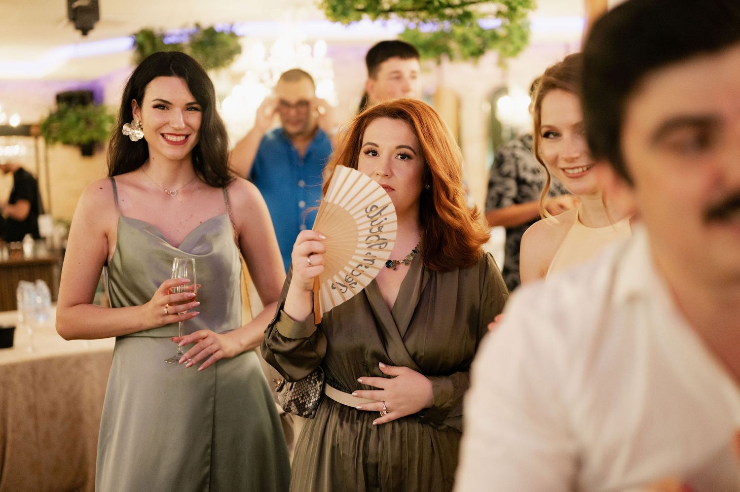 Wedding guests raise champagne glasses in celebration at an elegant indoor reception.