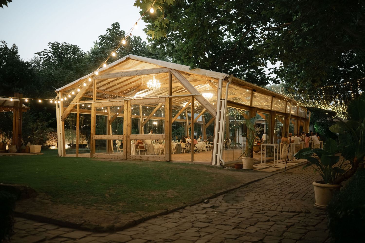 Rustic wooden barn venue with string lights illuminated at dusk creating a warm and romantic atmosphere.