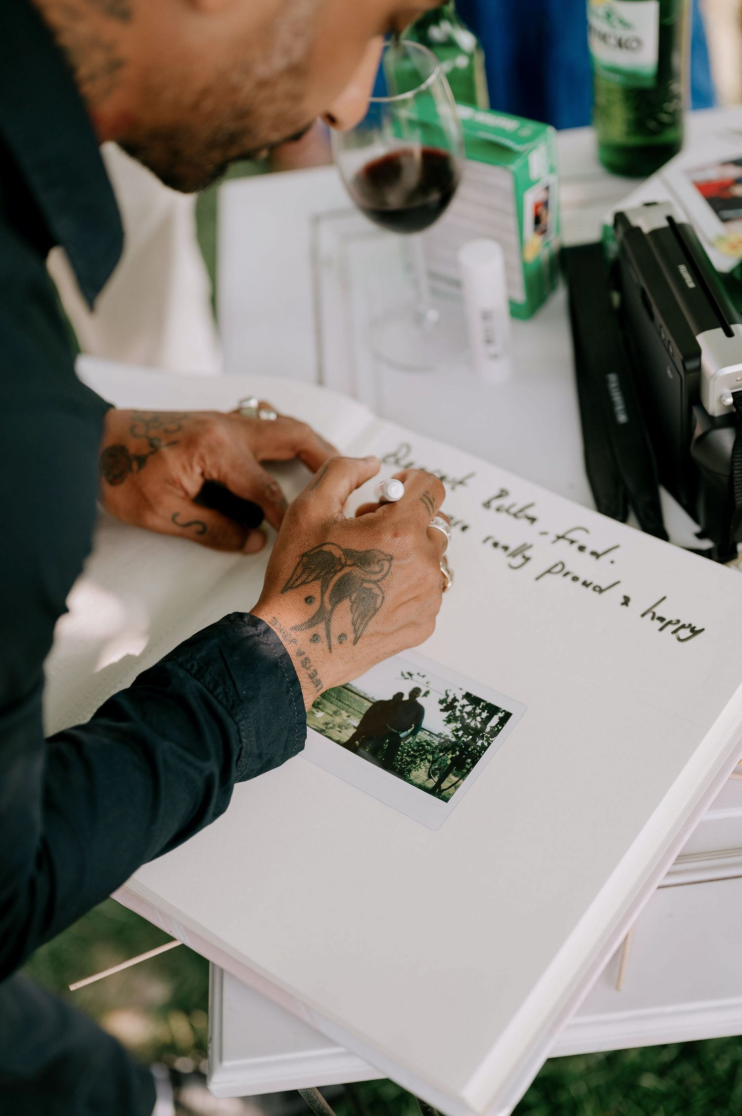 Guest signing a white wedding guestbook with photos and personal messages.