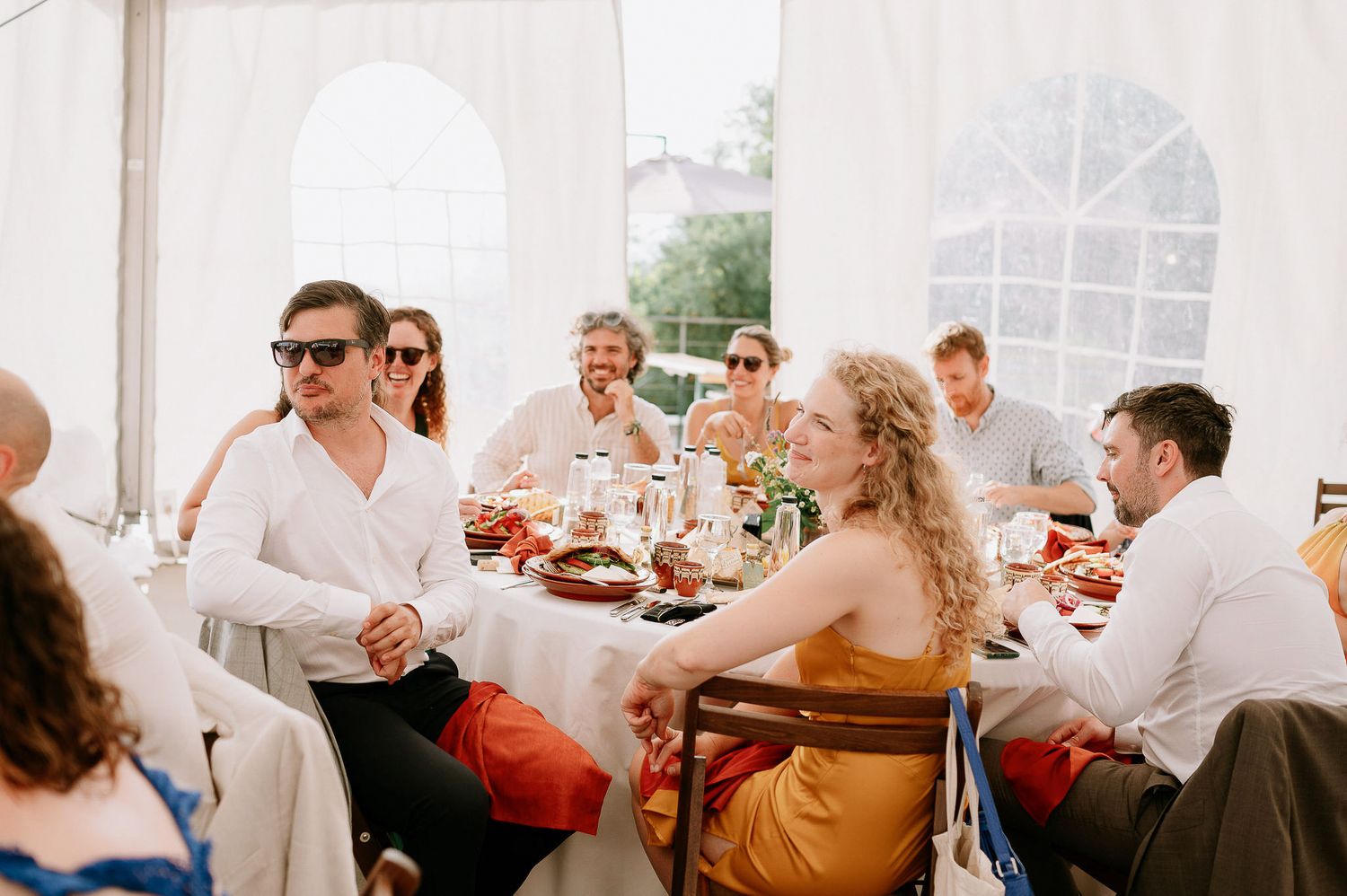 Wedding guests enjoying a meal inside a white tent reception venue.
