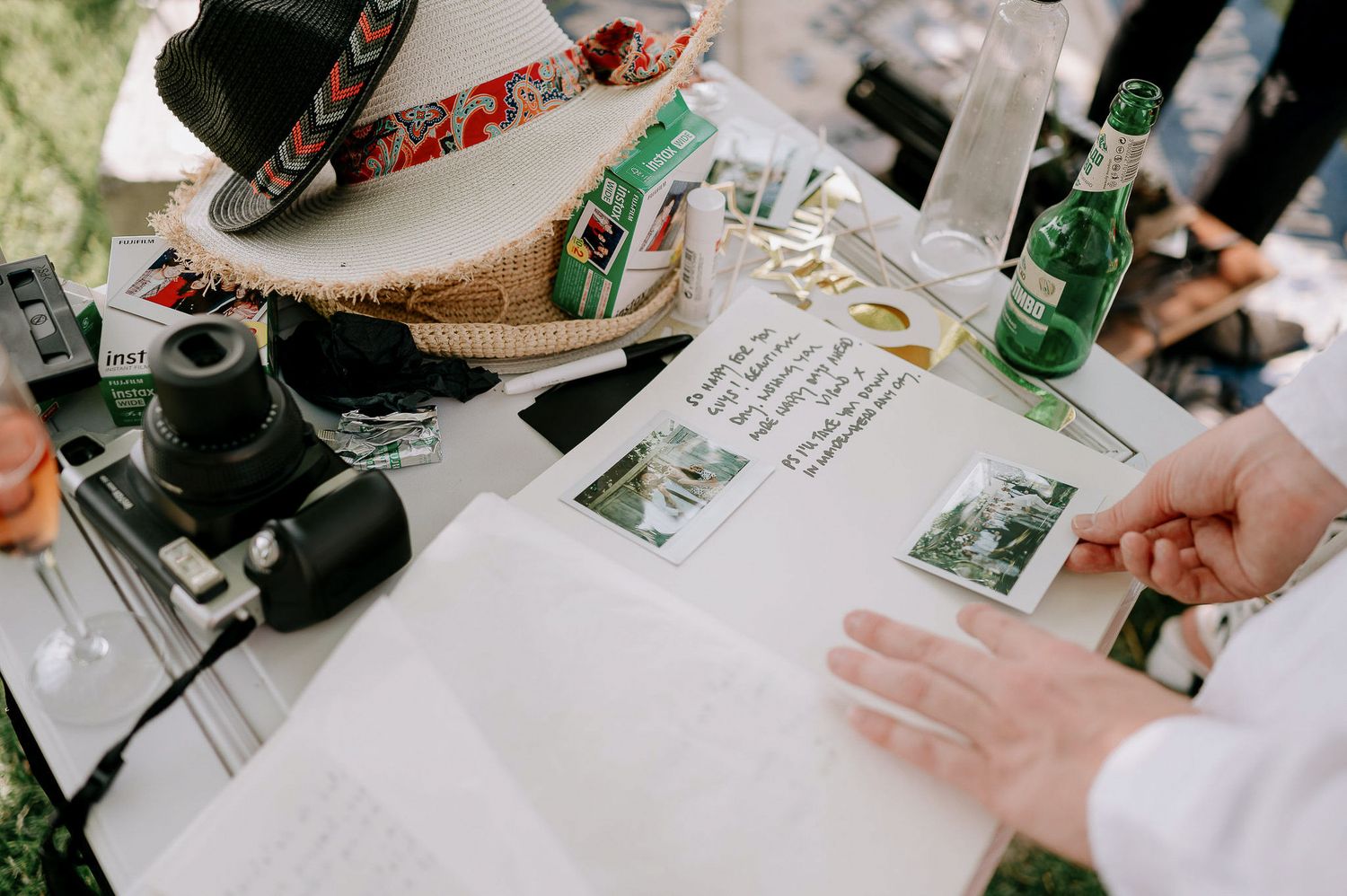 A wedding guestbook table with vintage cameras, drinks, and handwritten notes.