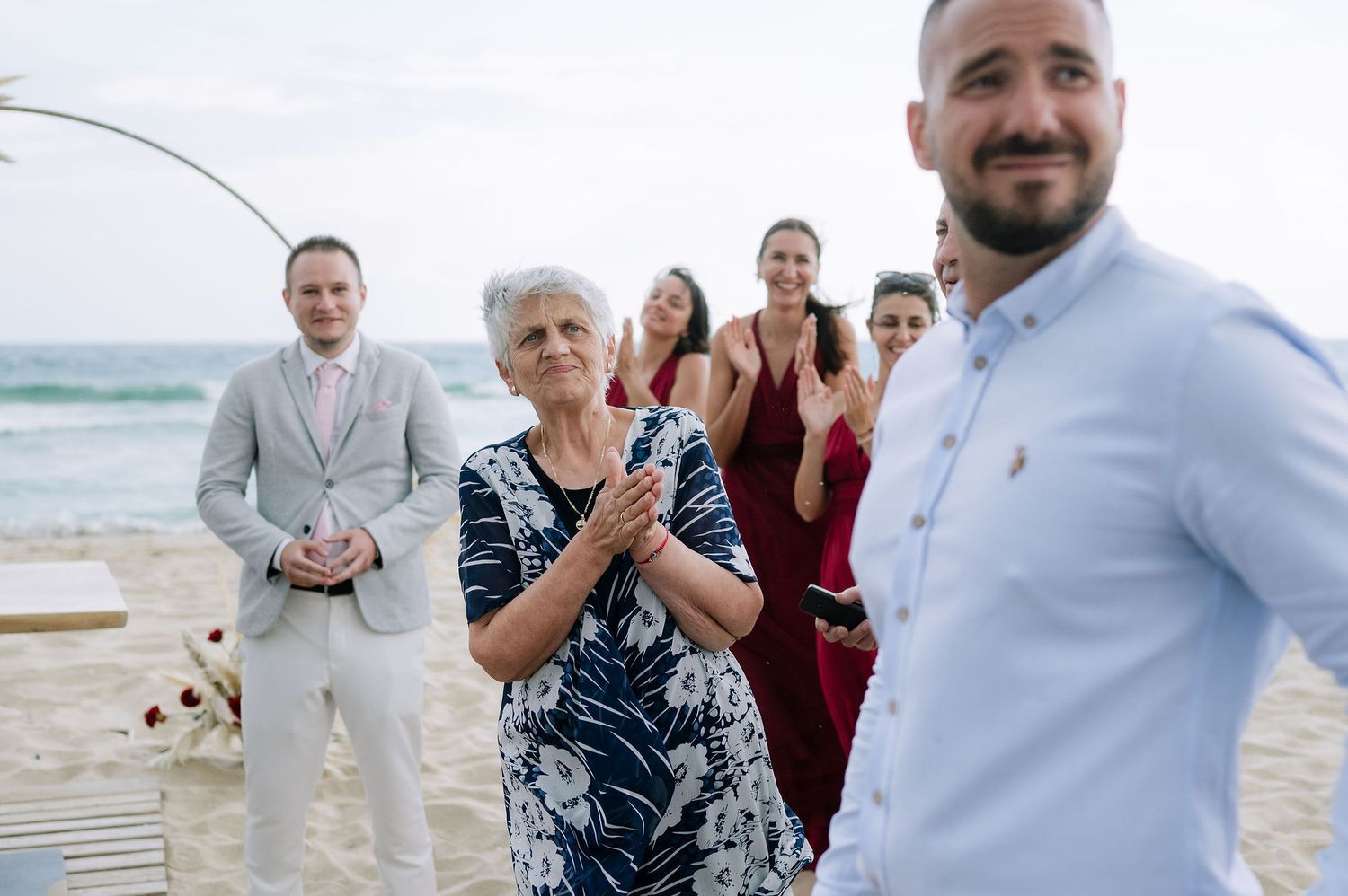 Wedding celebration candid moments captured on a beach boardwalk under overcast skies.