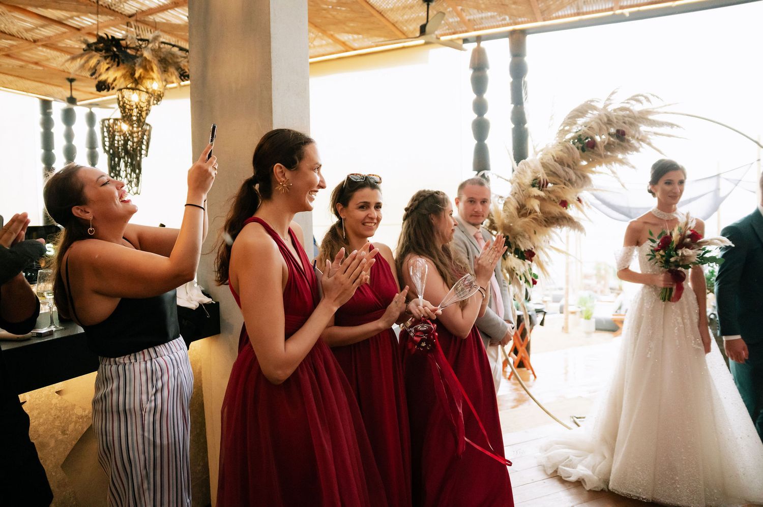 Wedding guests react emotionally during a special moment at an indoor reception venue with wooden ceiling.