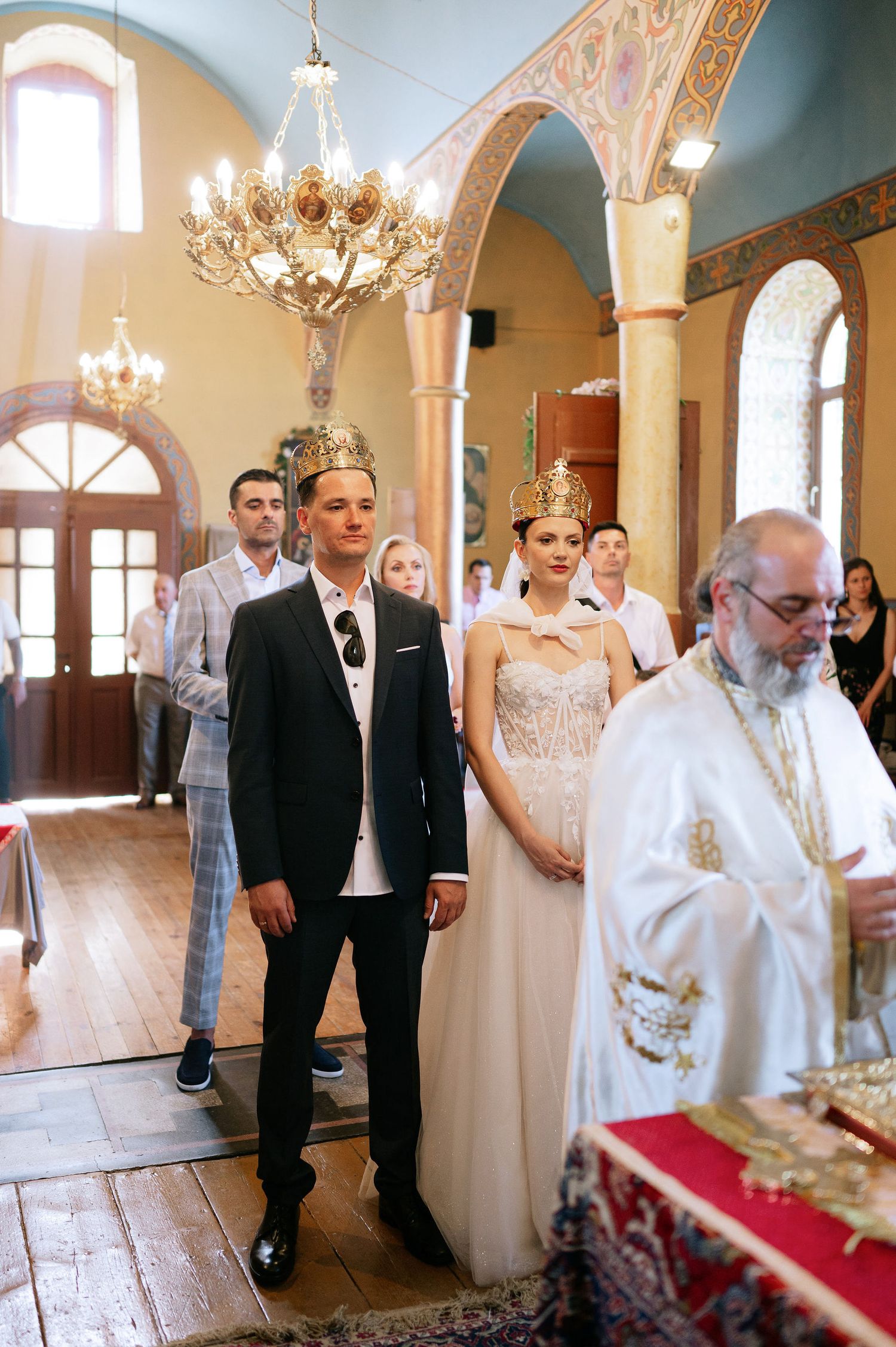 Traditional Orthodox wedding ceremony taking place in a beautifully decorated church interior.