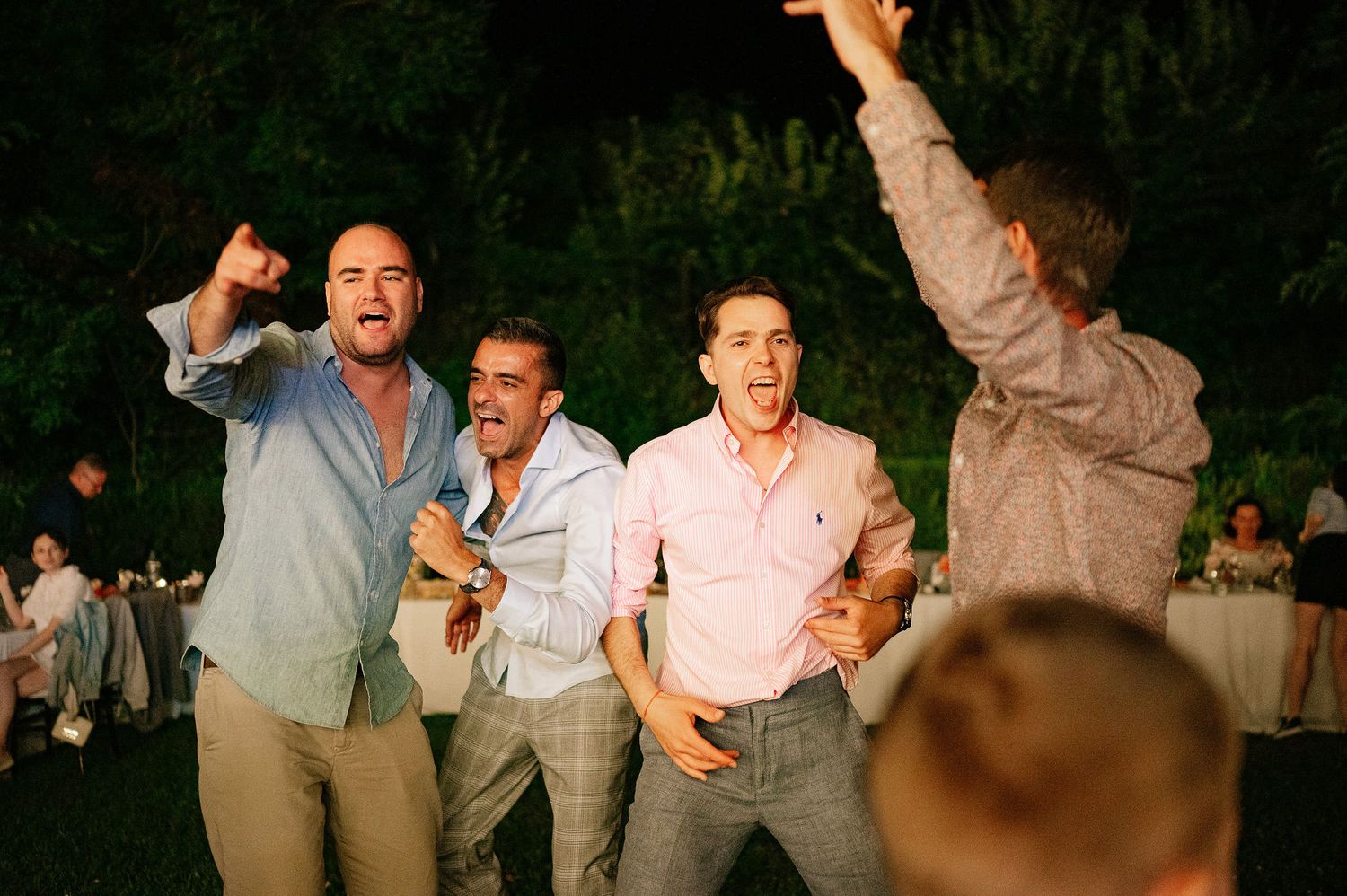 Wedding guests dancing and celebrating during a lively outdoor reception party.