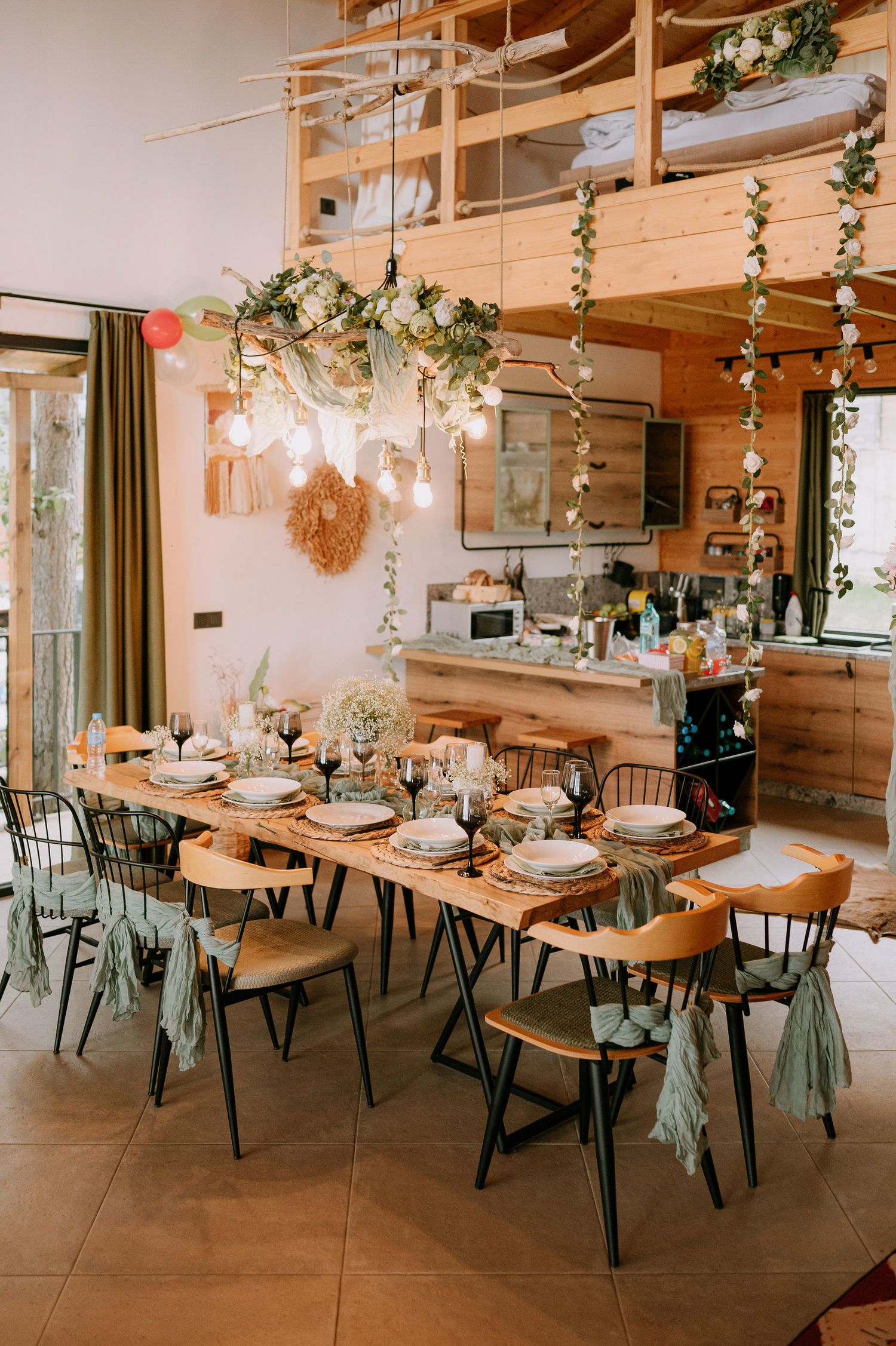 Wedding reception space featuring long wooden tables adorned with greenery and elegant place settings.
