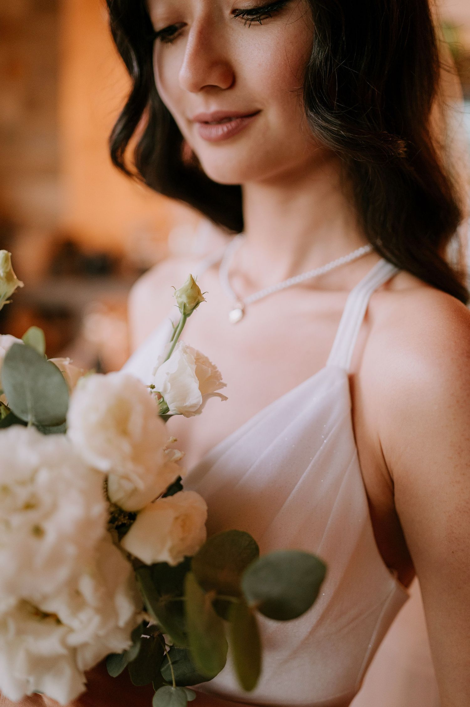 Elegant white floral arrangement with eucalyptus leaves against soft blush tones.