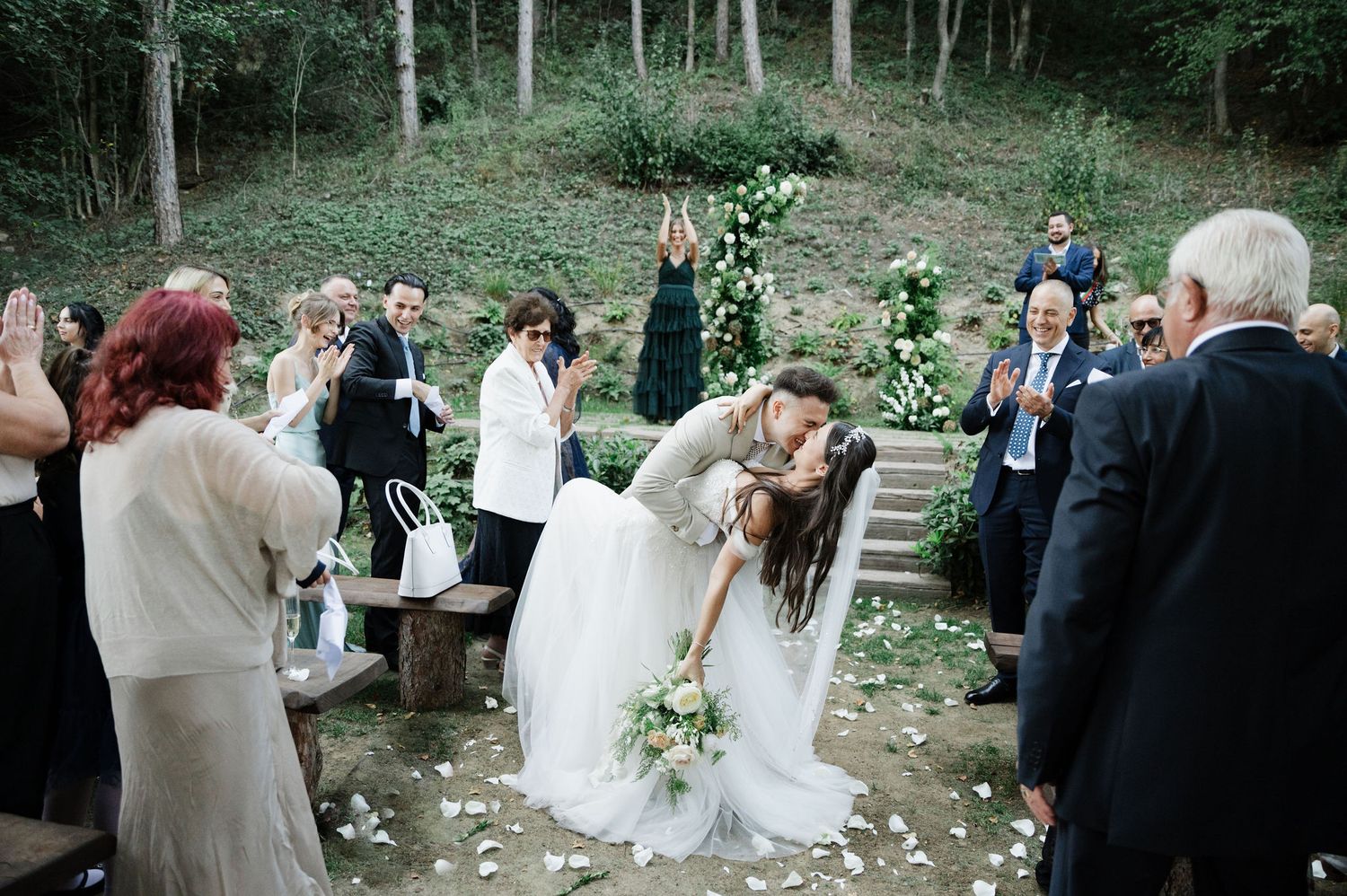 Wedding celebration takes place on rustic stone steps surrounded by forest landscape.