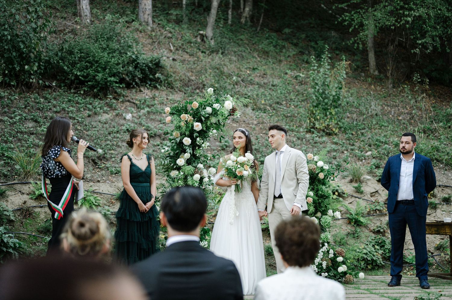 Wedding ceremony taking place on rustic stone steps surrounded by lush forest greenery.