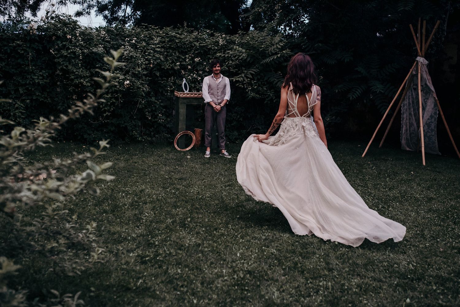 A romantic outdoor wedding ceremony setup with vintage decor and a pink flowing dress in a garden setting.