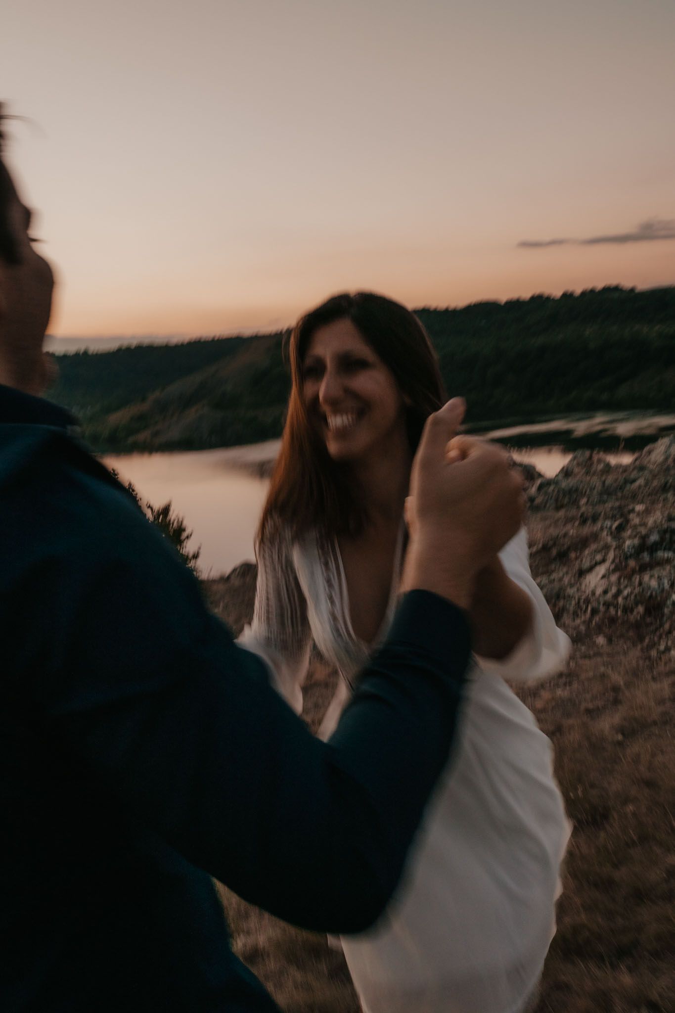 Couple embracing near lakeside during golden hour.