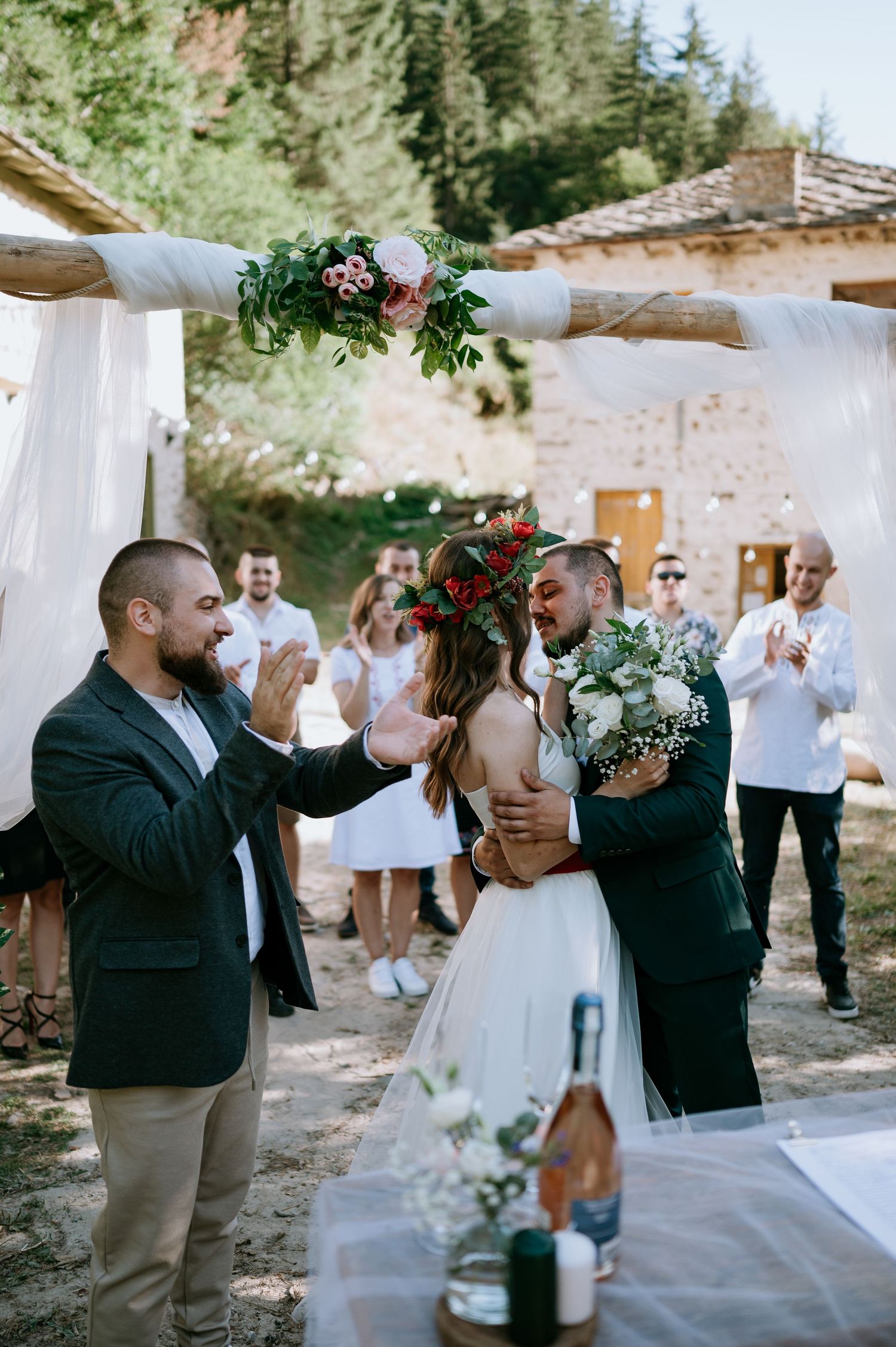 Wedding guests applaud during an intimate outdoor celebration under a decorated white canopy.