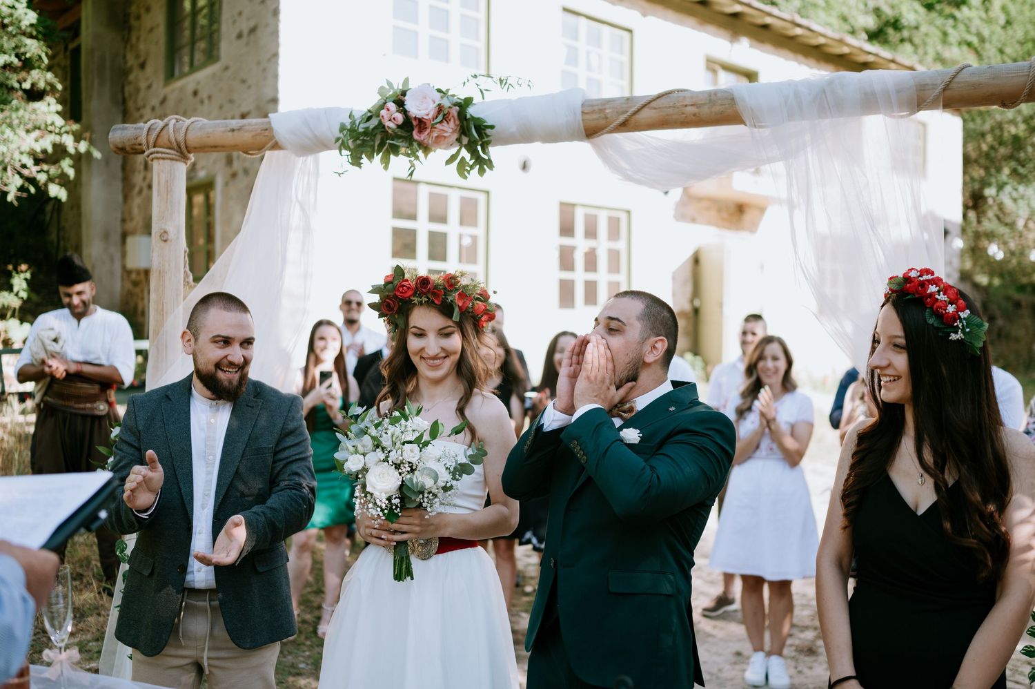 Wedding celebration with decorative white backdrop against rustic stone architecture.