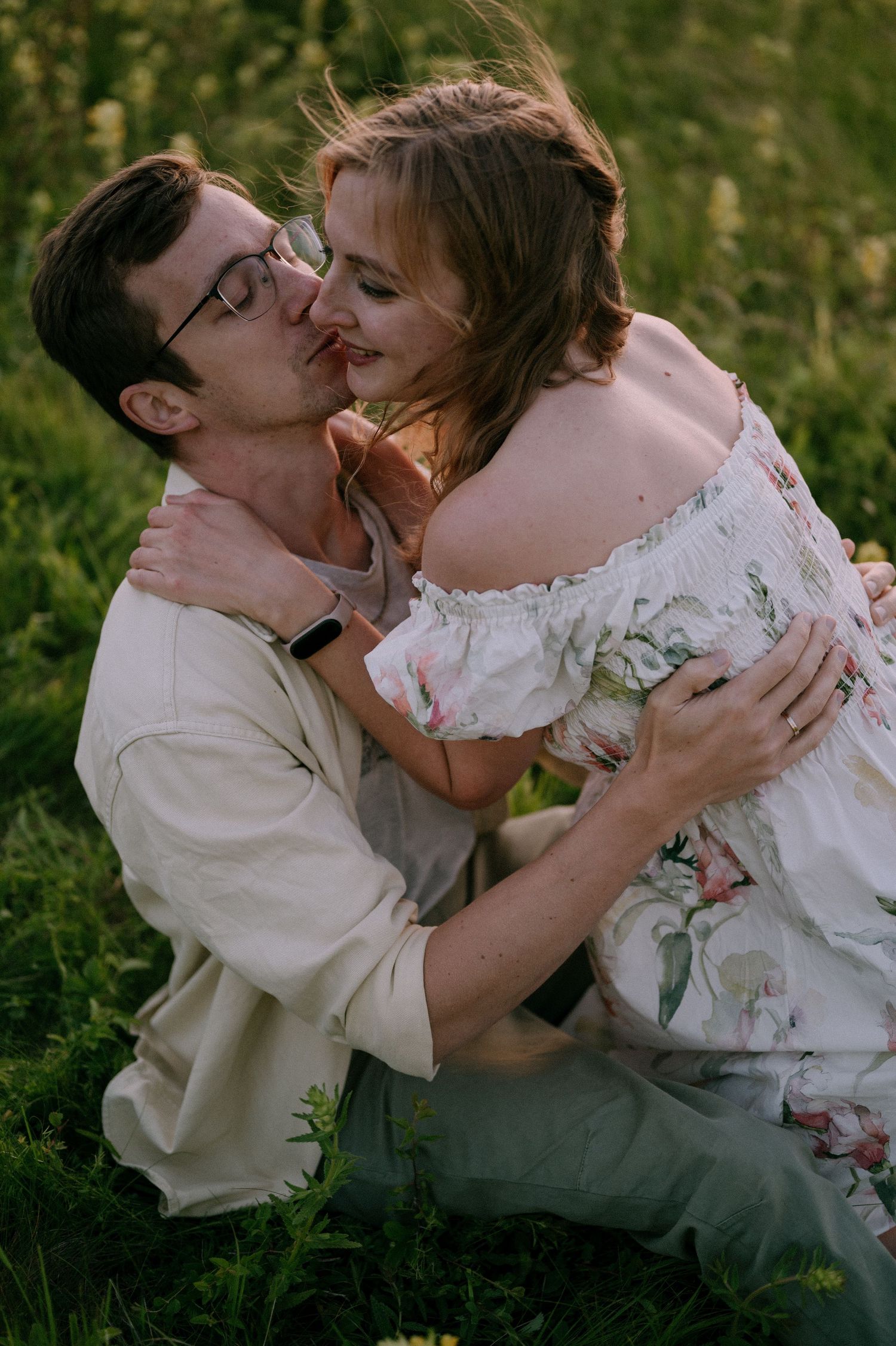 Intimate embrace shared between couple in flowering meadow during golden hour.