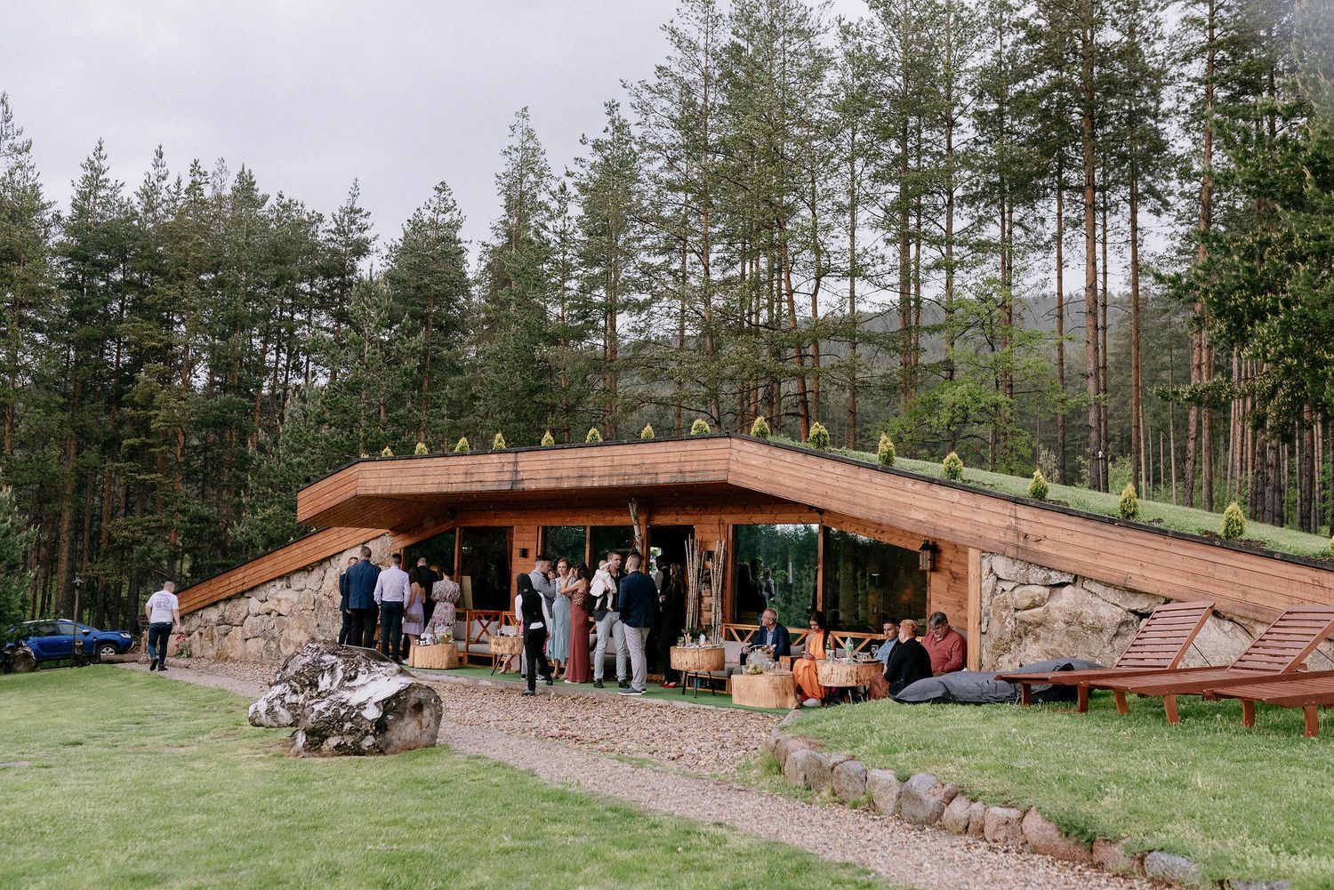 Panoramic view of rustic venue buildings and pathways surrounded by evergreen forest.