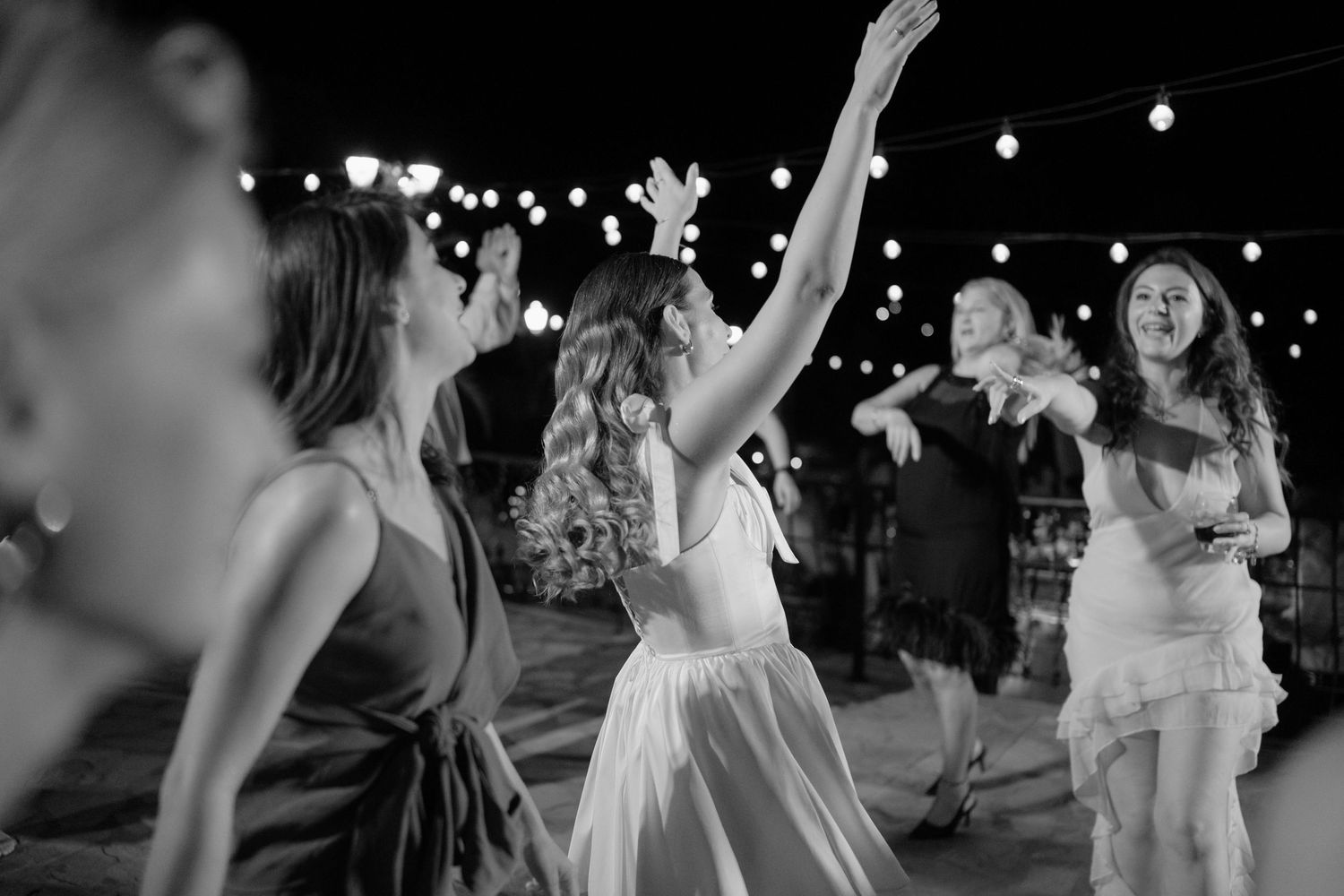 Wedding guests dance and celebrate on the dance floor during a reception in black and white.