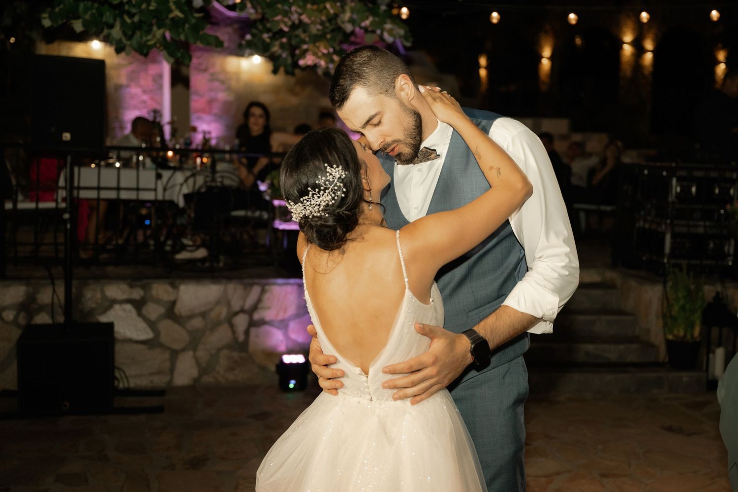 A couple shares a romantic dance at their wedding reception as guests look on in the evening.