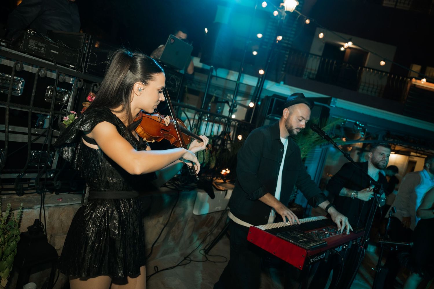 Musicians perform on stage with dramatic blue lighting and atmospheric effects at a live concert venue.
