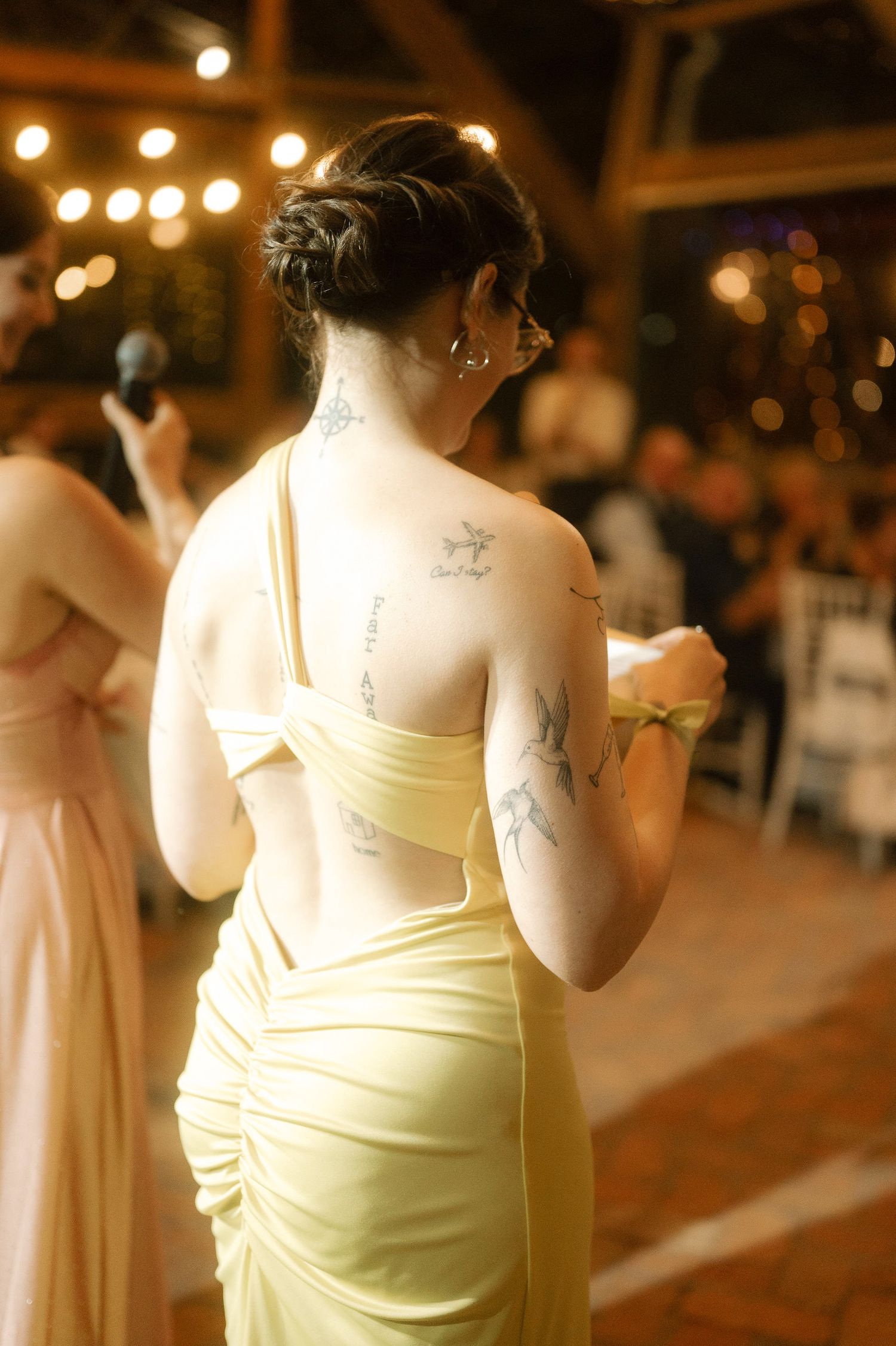 A row of bridesmaids in cream-colored dresses stand in line at an evening wedding reception with warm lighting.