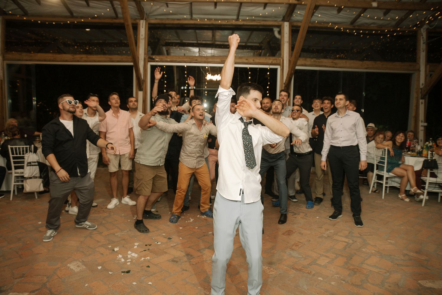 Wedding guests dancing together on a rustic wooden dance floor at an outdoor reception celebration.