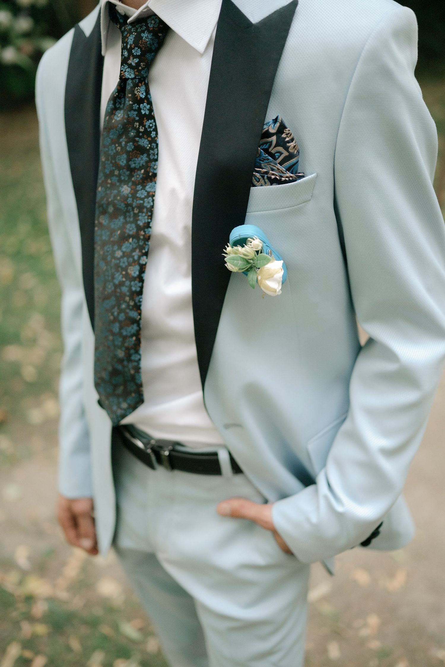 Close-up details of a light blue prom suit with patterned tie and pocket square showing formal attire styling.