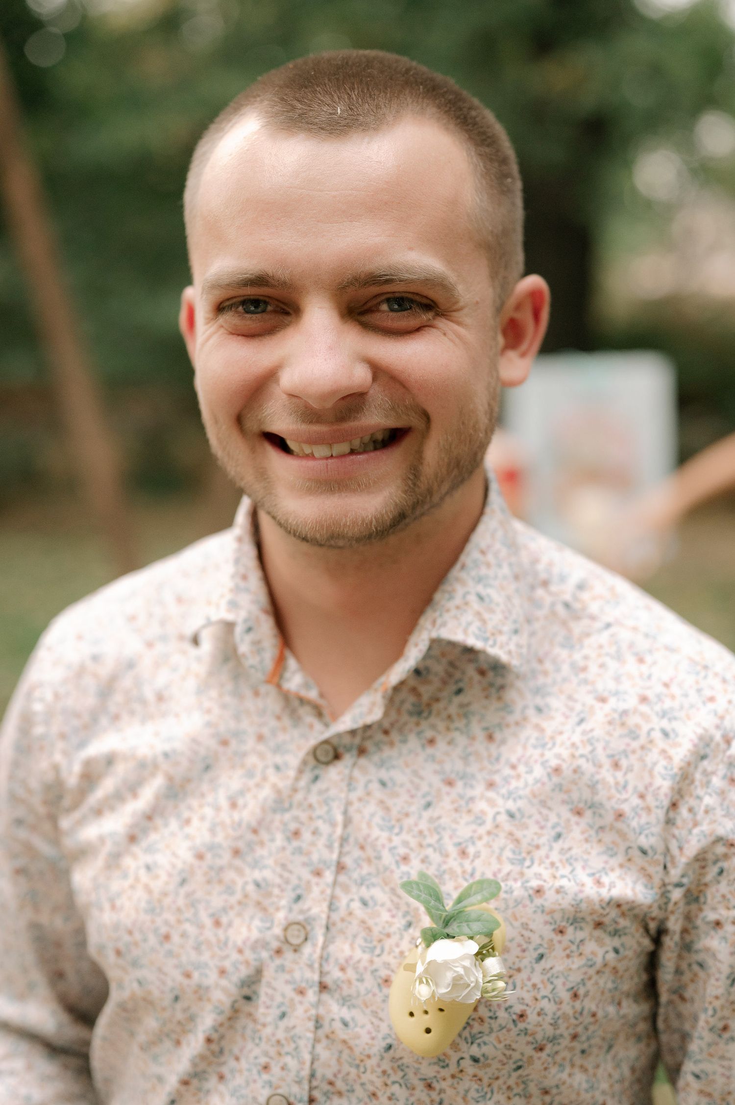 A series of five portraits showing someone wearing a floral print shirt and boutonniere in an outdoor setting.