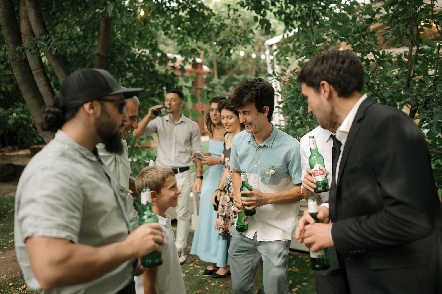 A group of people enjoying drinks and conversation in a lush outdoor garden setting.