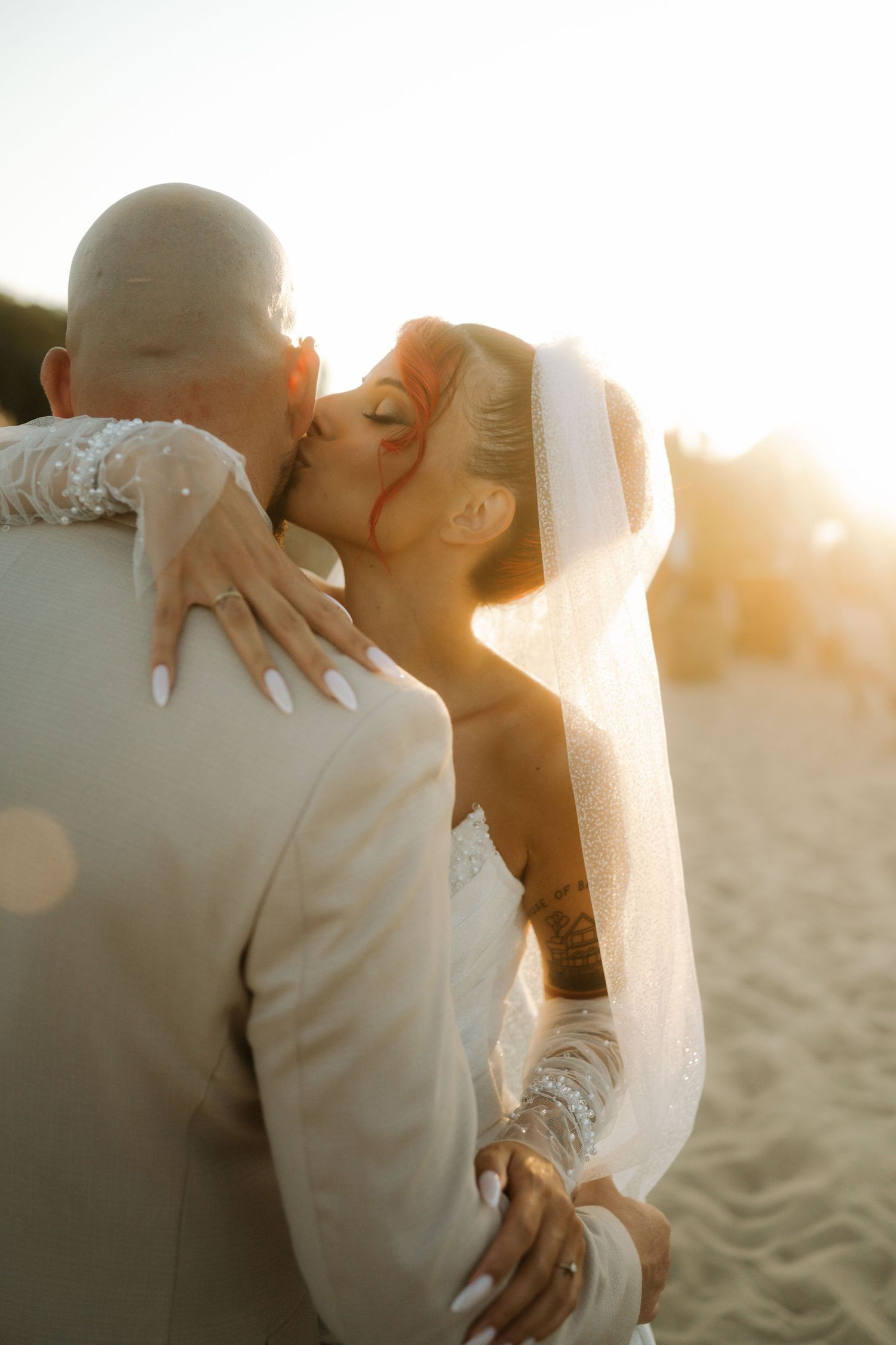 Tender moment captured between parent and baby on sandy beach at golden sunset.