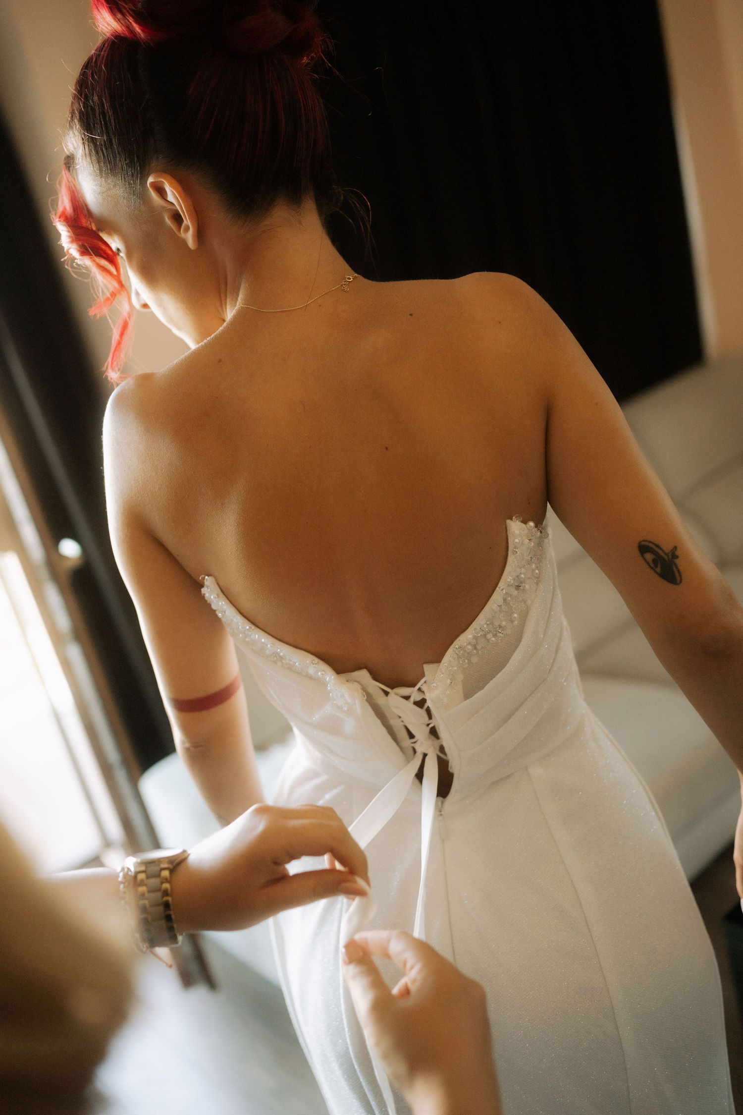 A series of images showing someone being laced into a white wedding dress with corset-style back detailing.