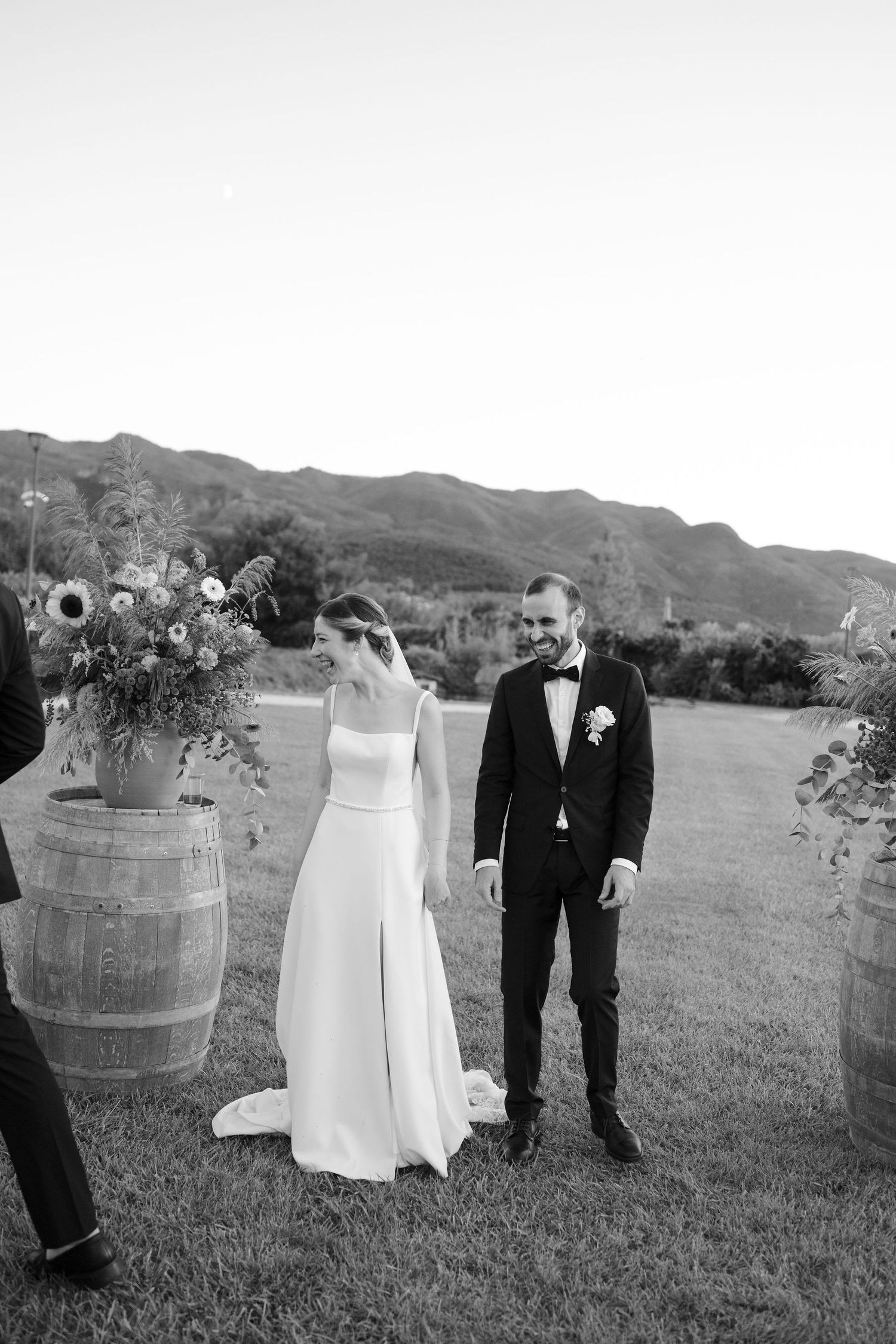 Black and white wedding photos showing couples posing outdoors with wine barrels and mountains in the background.