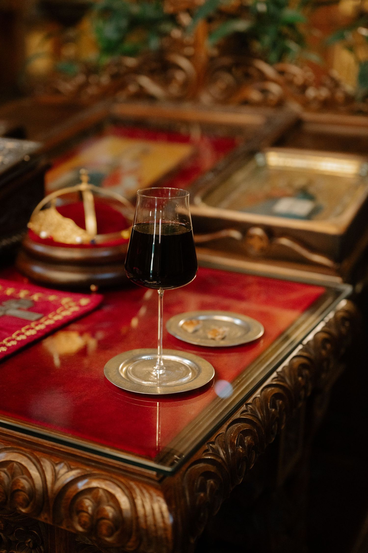 A wine glass sits elegantly on a dark wooden table with red placemats creating a warm, romantic dining atmosphere.