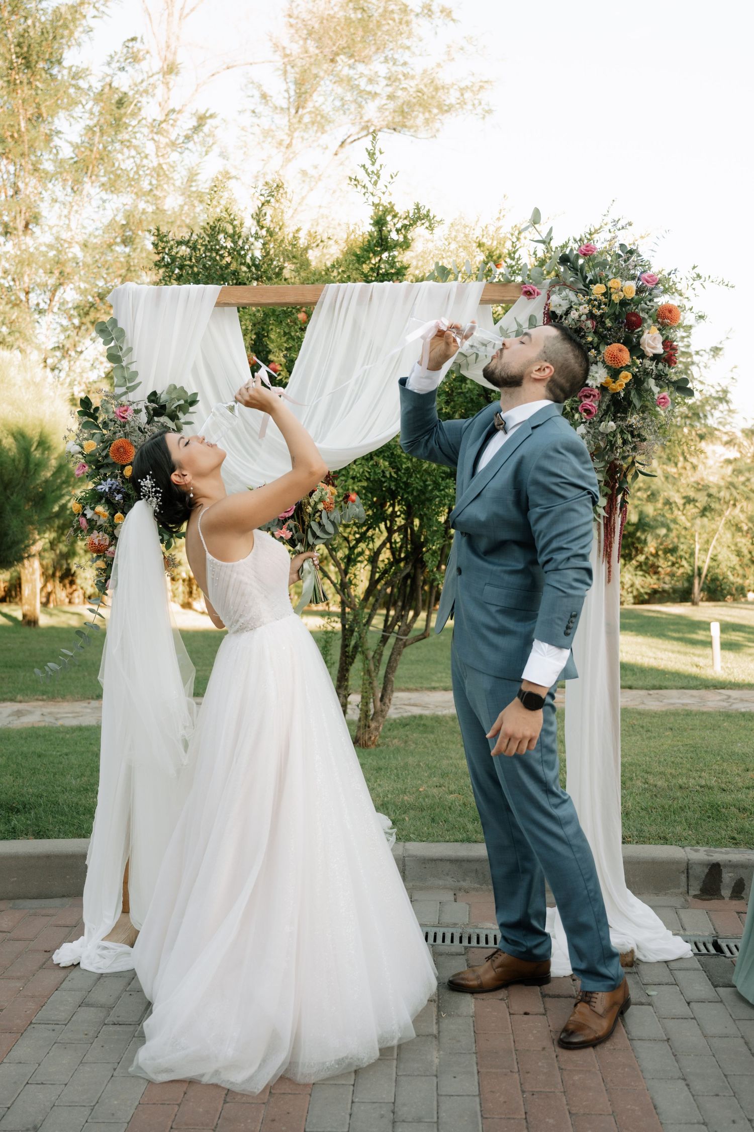 Newlywed couple celebrates with a fun champagne toast sequence at an outdoor garden wedding ceremony.