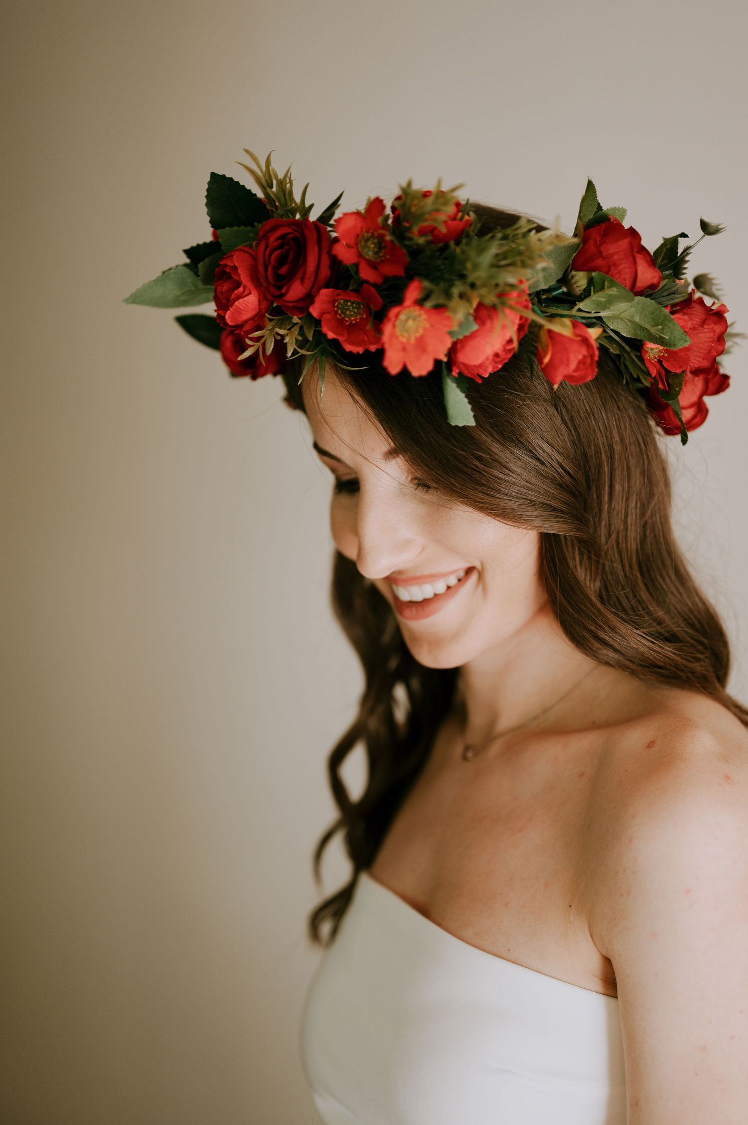 Side profile of figure wearing white dress and vibrant red rose crown.